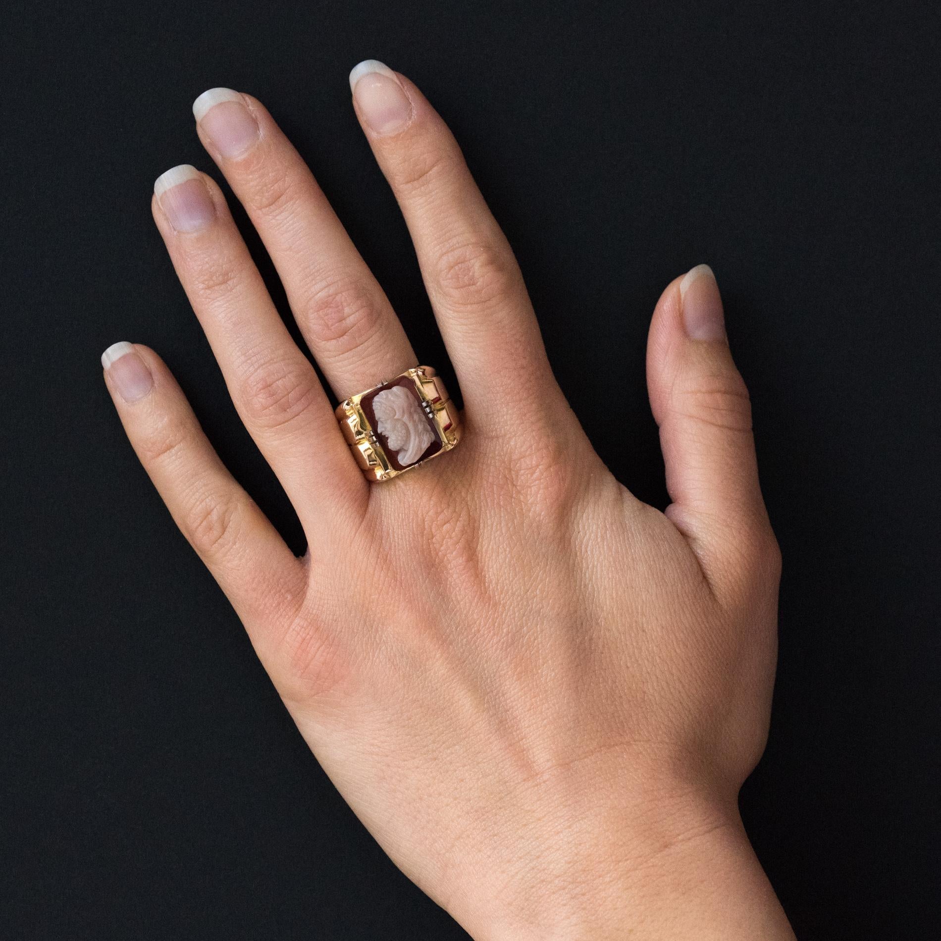 Ring in 18 karats yellow gold, eagle's head hallmark.
Large signet ring, it is adorned on its top with an agate cameo representing the left profile of Heracles retained by claws of white gold. On both sides of the palm patterns give the start of the