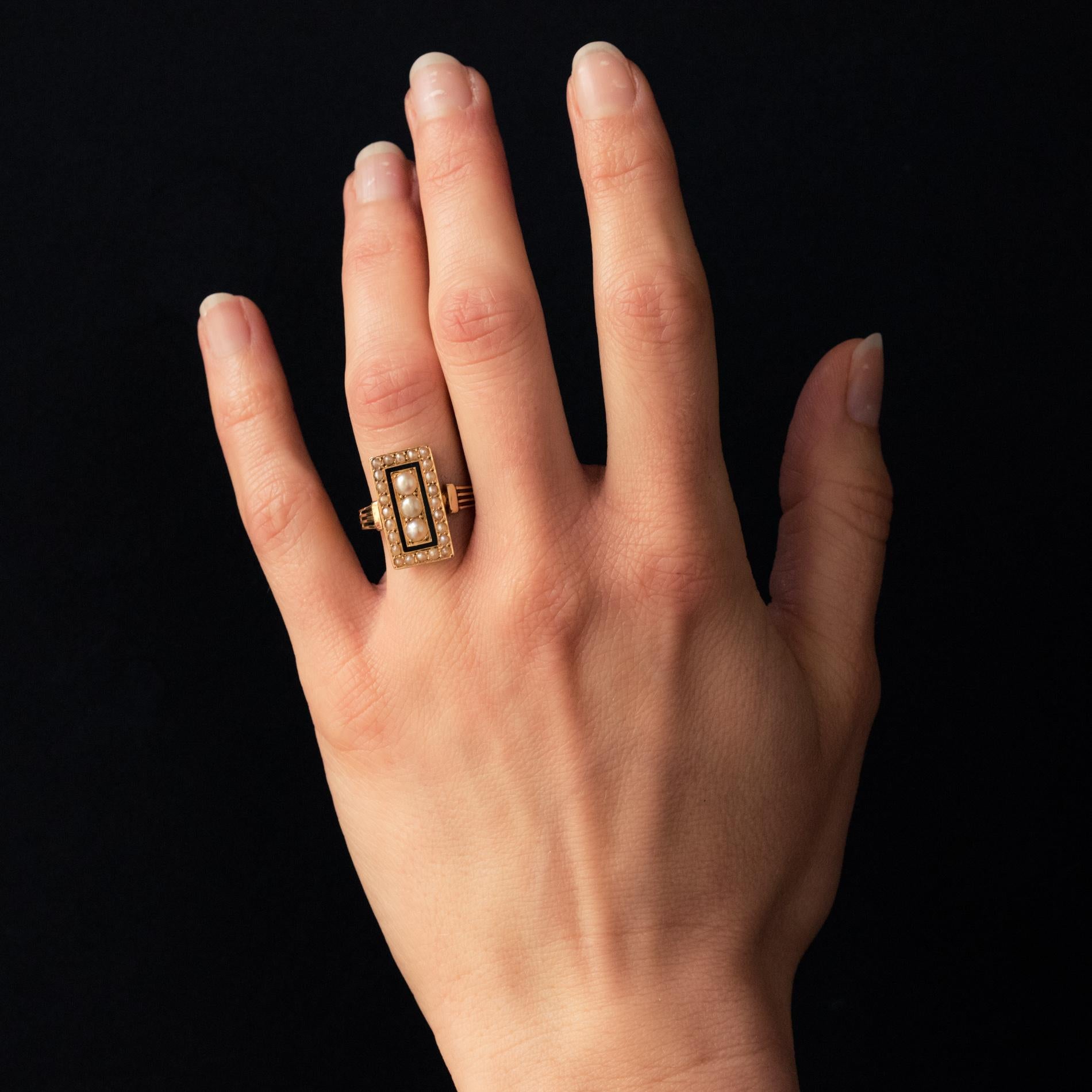 Ring in 18 karat yellow gold, owl hallmark.
Charming antique ring, it consists of a rectangular shaped setting set with half natural pearls. The natural pearls in the center are larger and surrounded by a streak of black enamel. The ring consists of