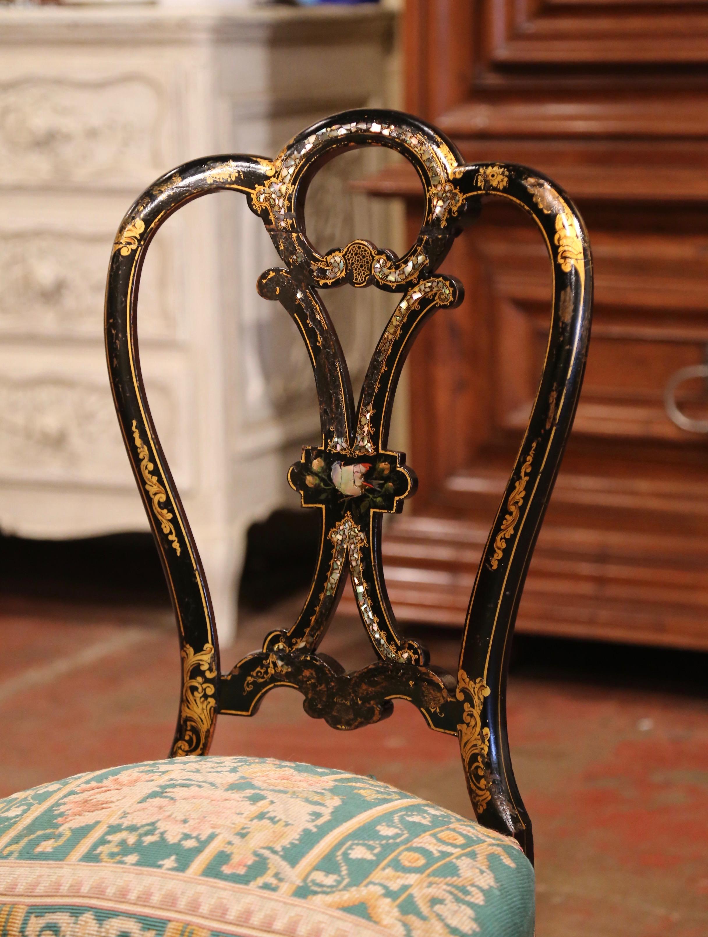 This elegant and colorful antique chair was crafted in France, circa 1870. The petite chair stands on cabriole legs over a bombe scalloped apron; it features an elaborate curved ladder back decorated with a shiny, black lacquered paint and