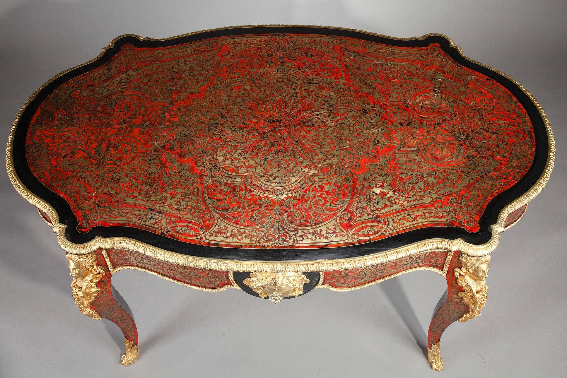 Large table in Boulle marquetry in brass with a rich ornamentation of gilt bronzes. The table top is rimmed with a gilt bronze mount, finely chiseled with ova and foliages. Two satyr and two Maenad heads adorn the underside of the table top. It is