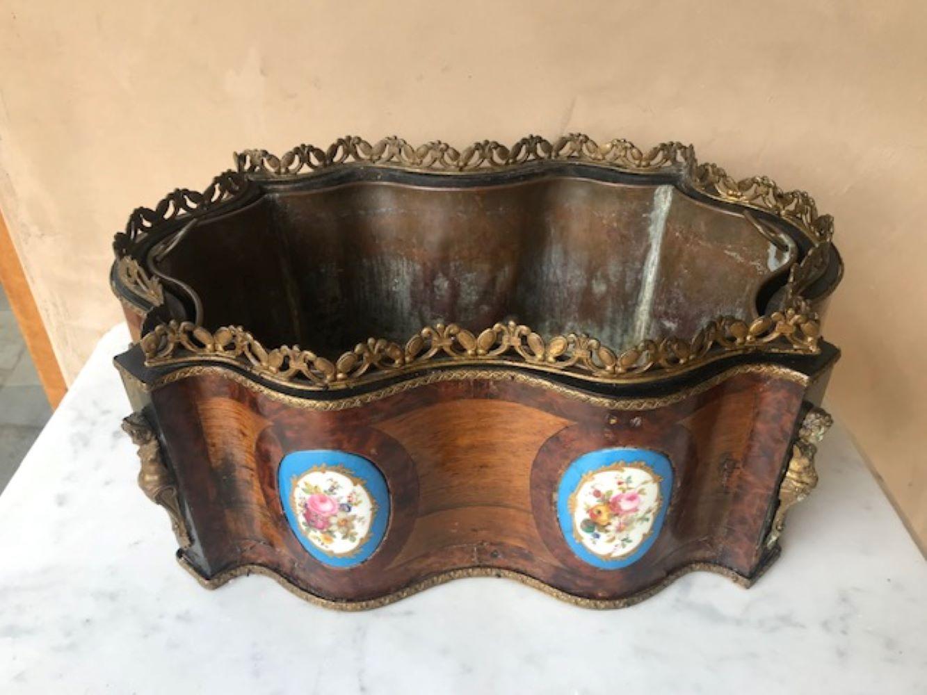 19th Century French rosewood and bronze Napoleon III cachepot / jardiniere / wine cooler. It is made of inlaid wood, bronze handles, two figural bronze impediments, and bronze top decorative lining and two porcelain tiles. The wine cooler has a