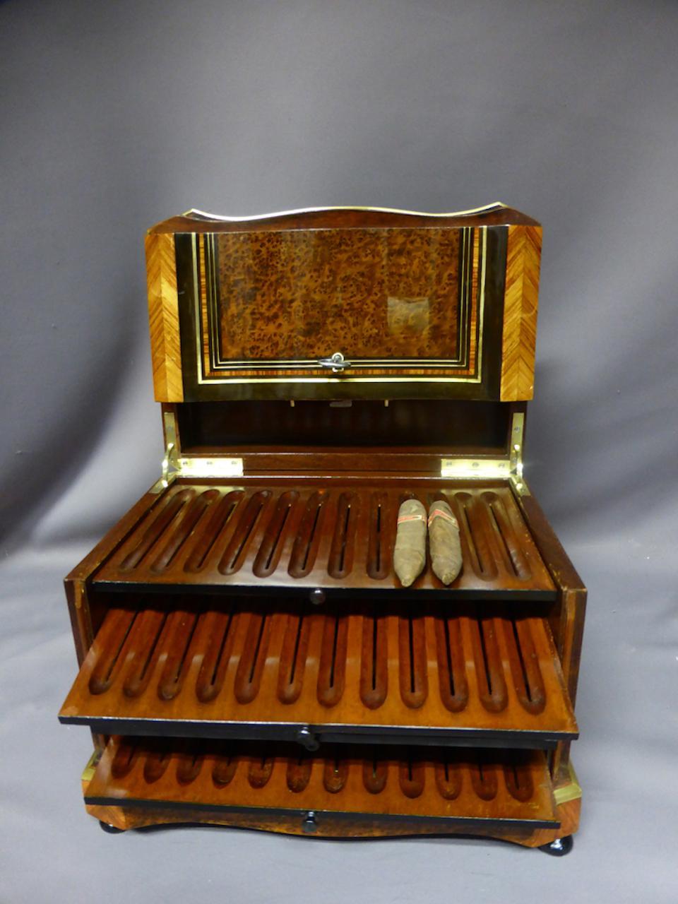 Cave à cigares XIX en loupe et marqueterie. 
Cette boîte comporte quatre porte-cigares et un tiroir. Un cartouche en marqueterie
et la nacre orne le dessus de la boîte.
Excellent état et qualité.