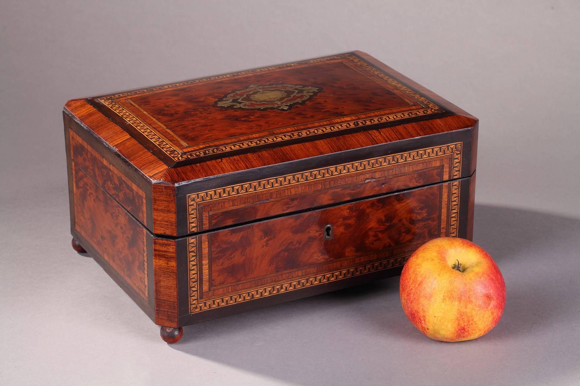 Varnished, burl wood sewing box, decorated with Greek frieze and brass inlays. The box contains a mirror and sewing utensils made of bone and brass, as well as two small glass flasks. The tray of sewing tools can be removed to reveal the double