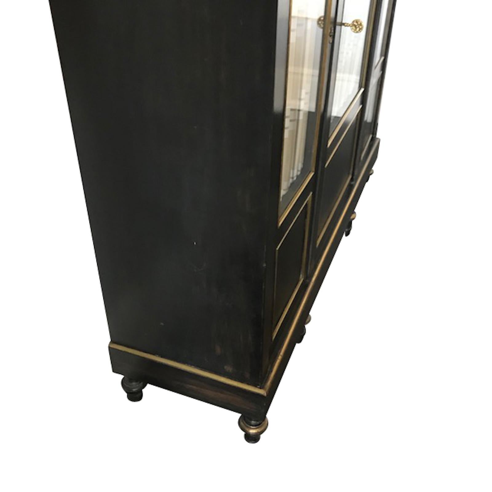 19th century French Napoleon III ebonized black cabinet with decorative brass details.
Original glass front panel doors.
Three interior wooden shelves.
Two are available and sold individually.