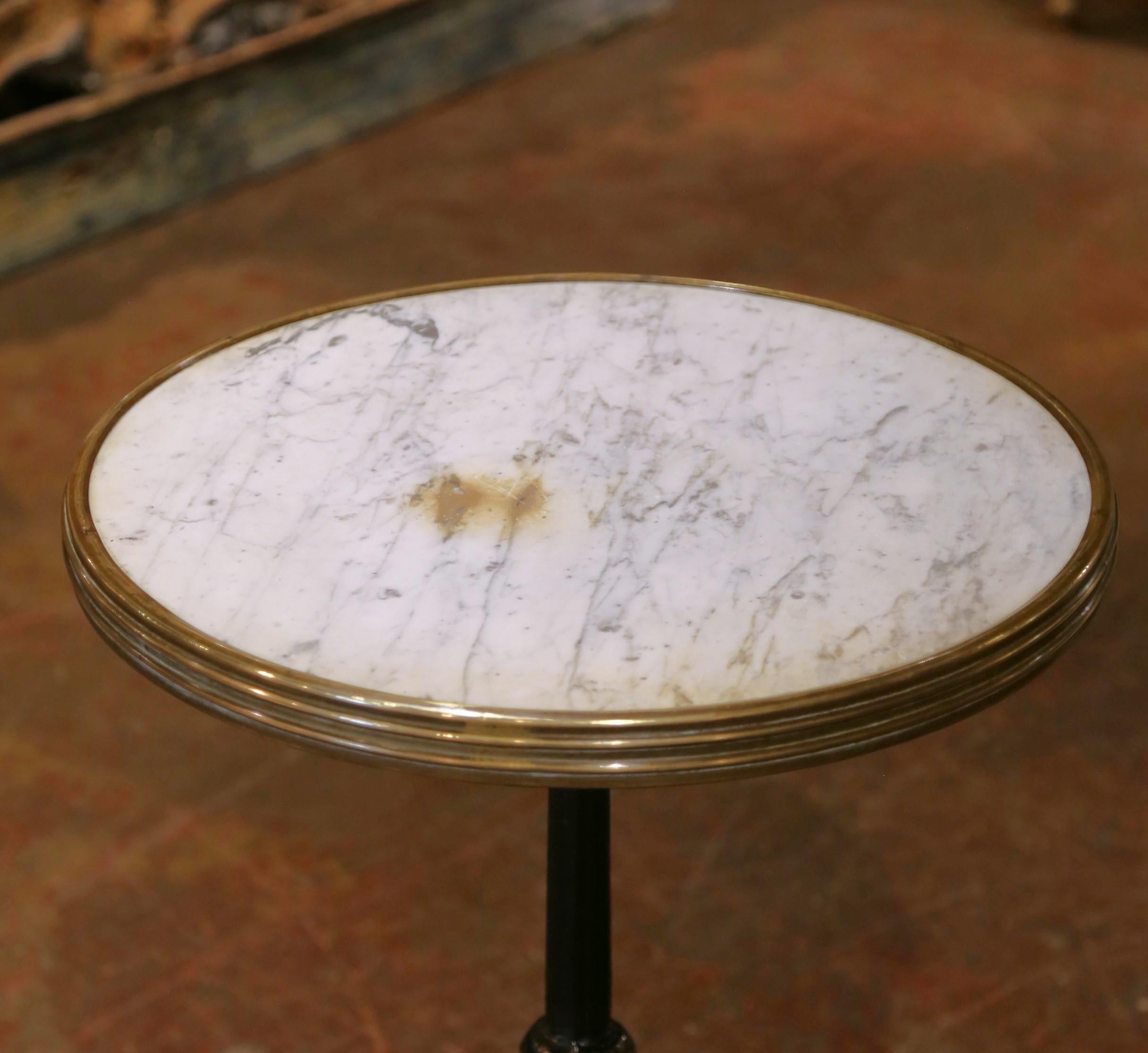 Bring Parisian charm to your space with this elegant bistro table from the Napoleon III period, crafted in France circa 1880. The inset round white marble top is accented with soft gray veining and enclosed within a fluted brass rim, adding a