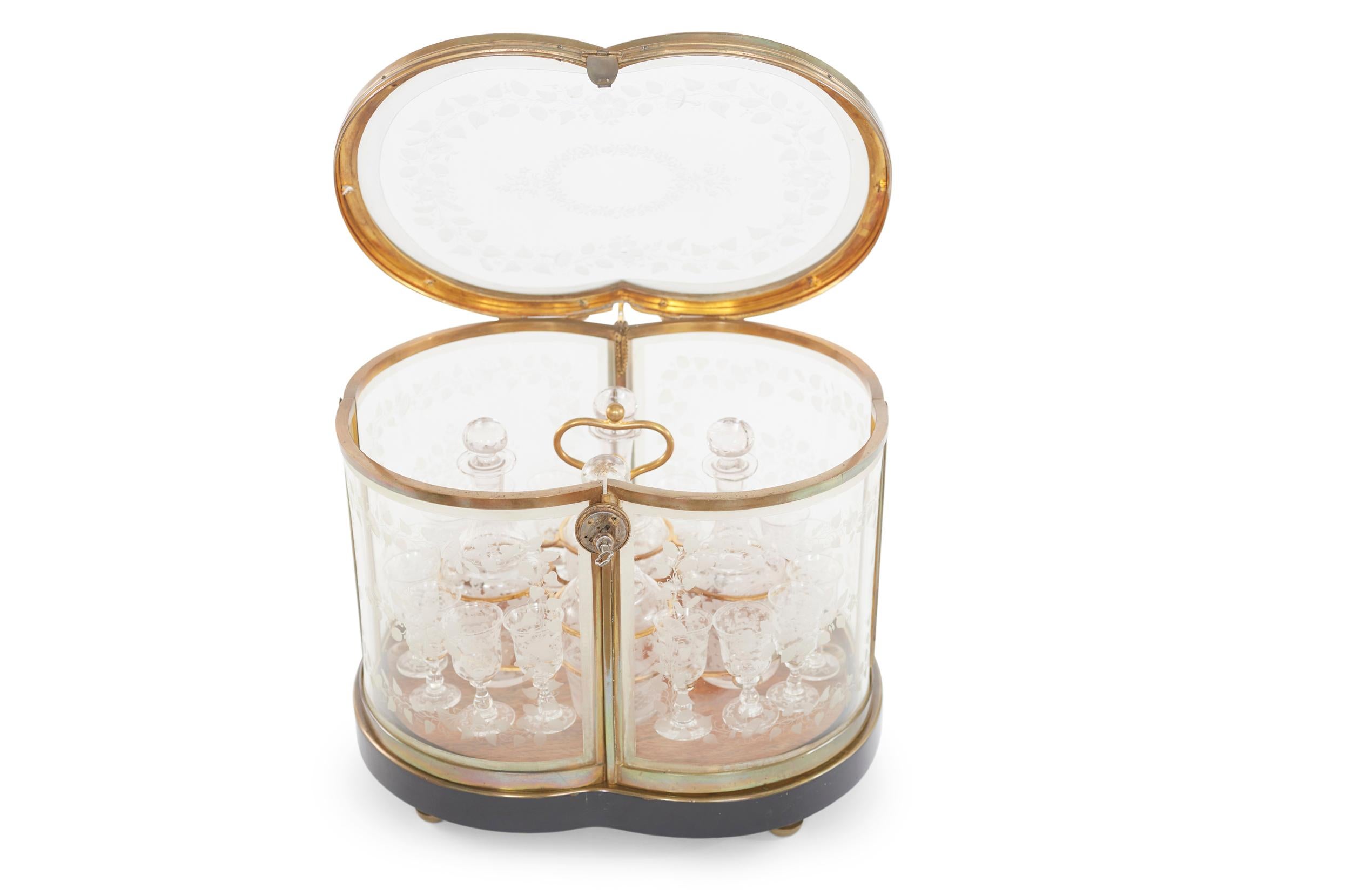 19th Century Napoleon III engraved glass and gilt bronze metal cave a liqueur. The cave feature an hinged lobed lid opening to hinged front panels and a removable stand centered by four stoppered decanters and sixteen footed glasses, The ebonized