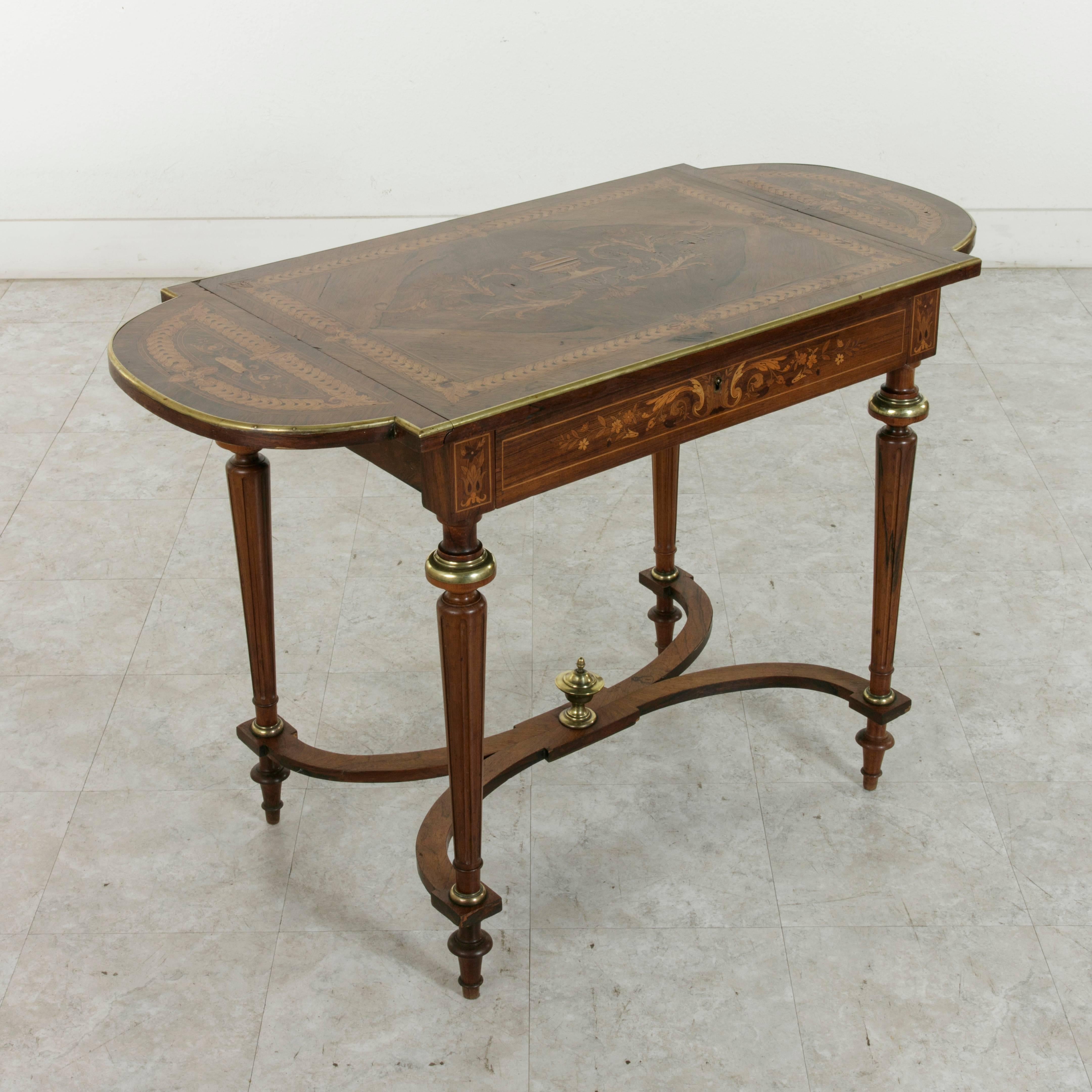 This exceptional French drop-leaf tea table from the Napoleon III period features intricate marquetry on all sides of walnut, palisander, lemon wood, and other exotic fruitwoods. The bookmatched palisander top displays detailed inlay in the form of