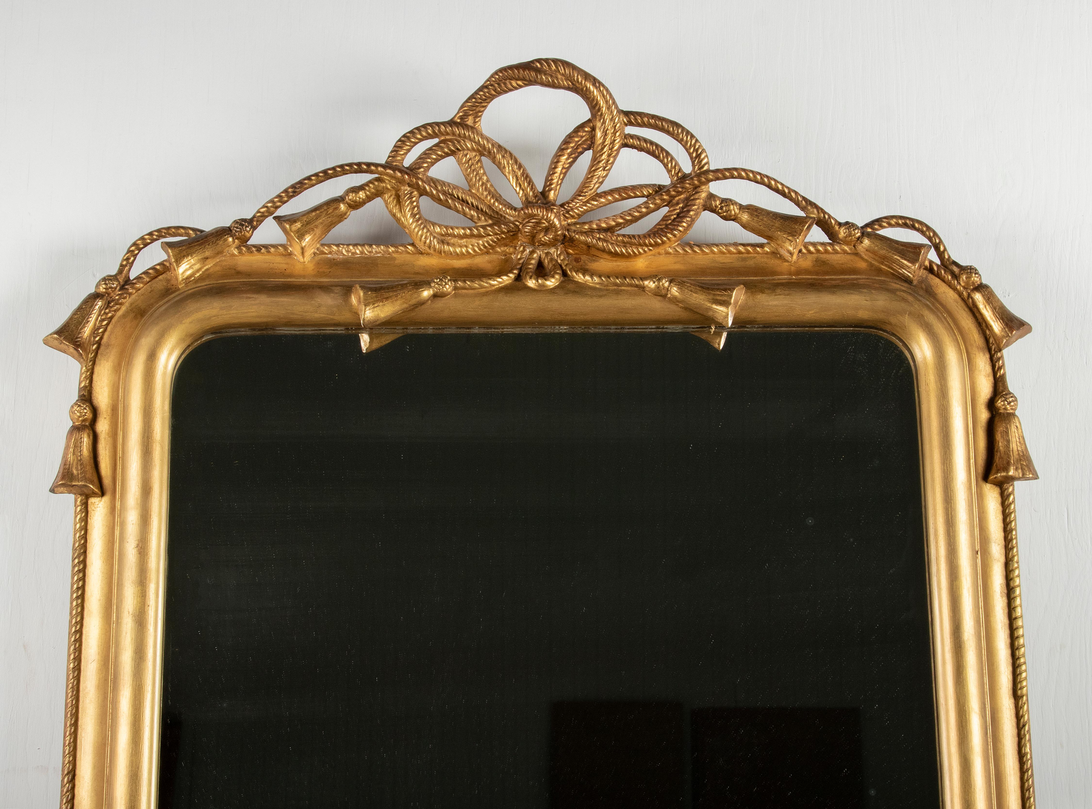 An elegant antique mirror with a crest of cords and tassels. Made in France, circa 1860 at he end of the Napoleon III period. The frame is made of pinewood, the moldings of there frame and rope and tassels are made of gesso. 

Originally the