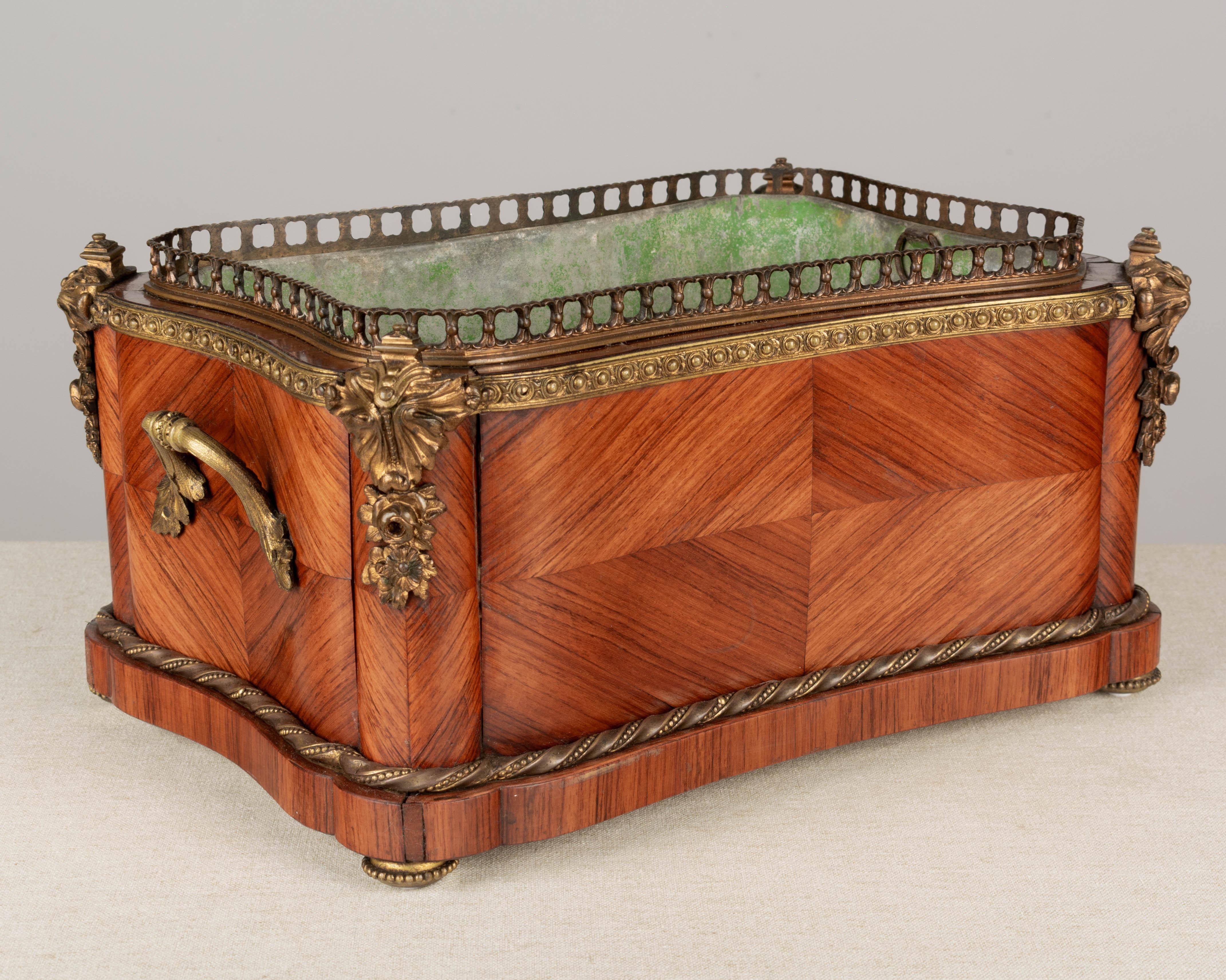A 19th century French Napoleon III bronze-mounted mahogany marquetry jardinière with unusual large rectangular form. Original unpolished cast bronze corner ornaments, rope trim, gallery and handles. Green painted zinc liner was repaired and may not