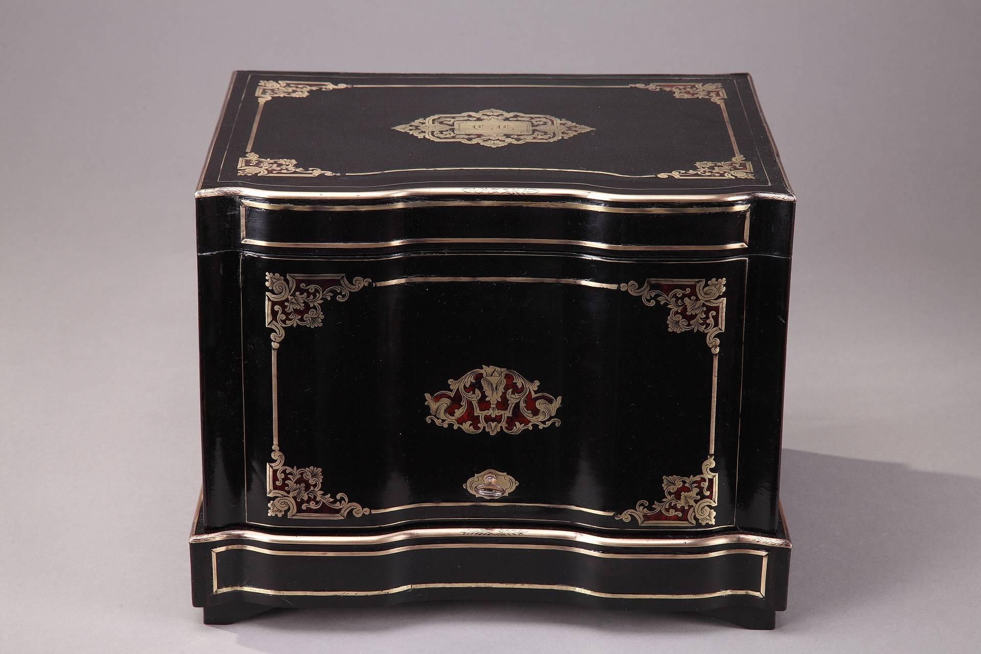 Liquor cellar in brass inlaid ebony with crystal glassware. The top of the box is engraved with the initials of the owner. Front and top sides are decorated with golden rinceau, foliages and interlacing. The interior is provided with a removable