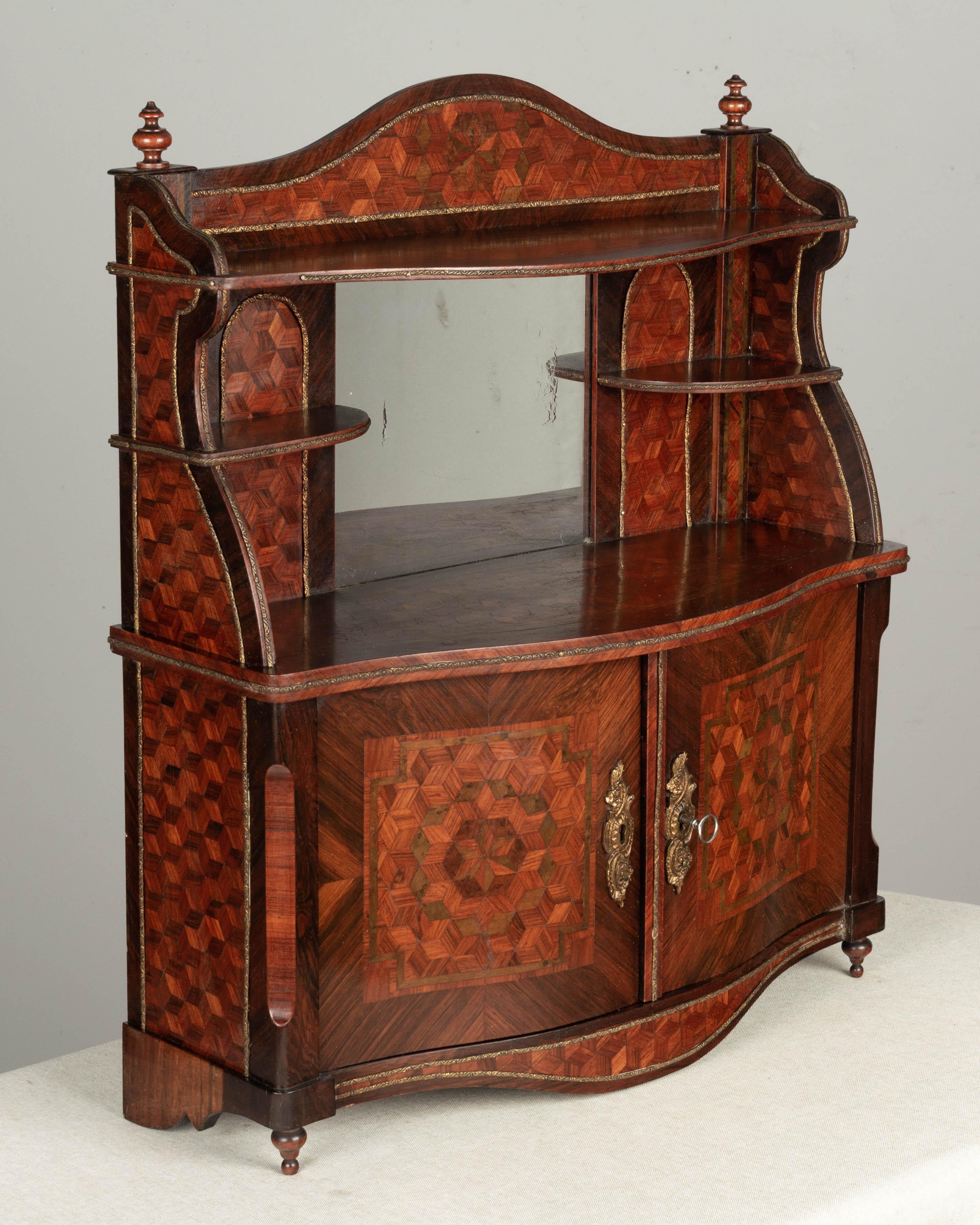 A 19th Century French Napoleon III miniature wall cabinet with fine quality marquetry inlay of rosewood, walnut and mahogany. Beautifully detailed with brass trim and escutcheons and turned finials. Mirror with old silvering. Working lock and key.