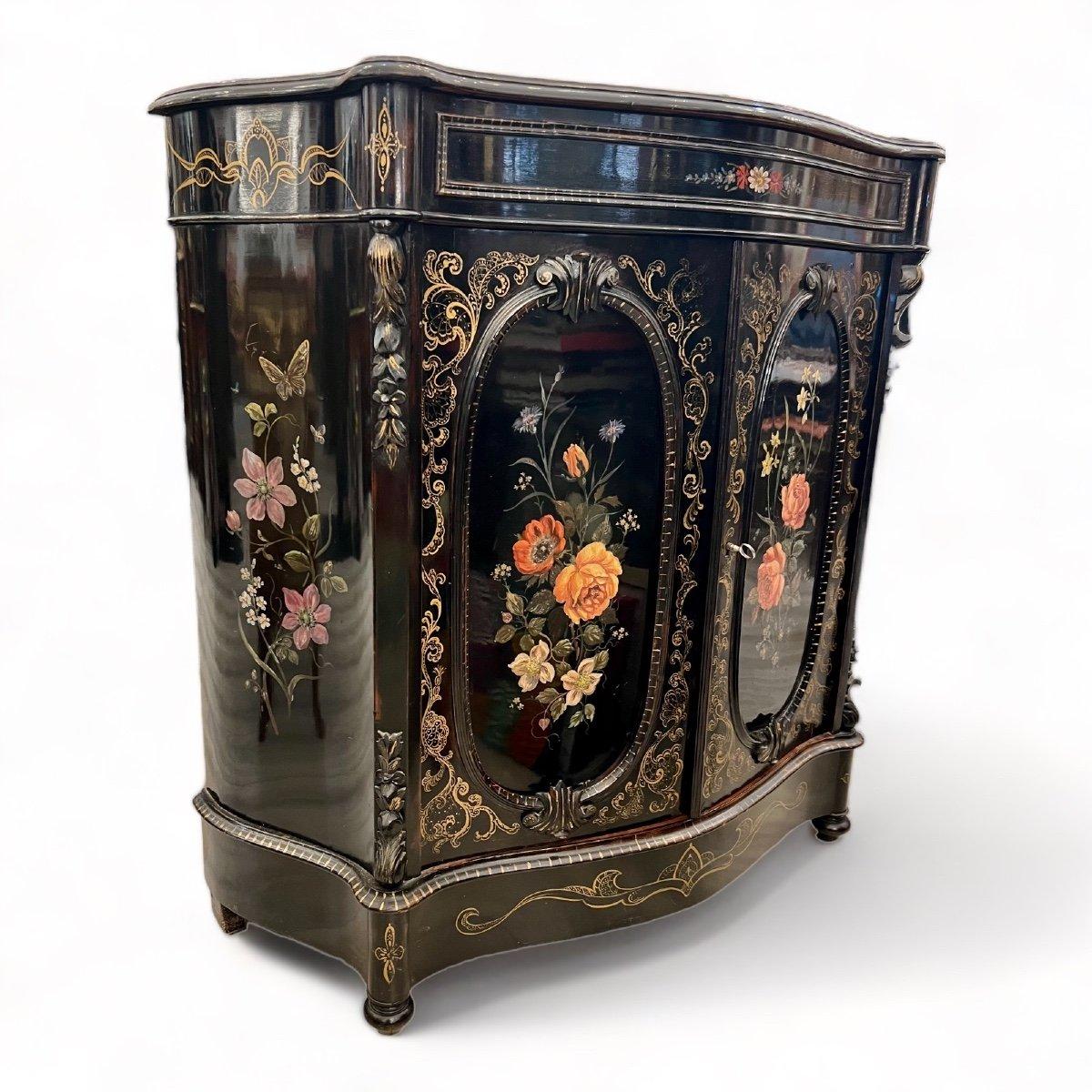 We present to you this unique 'meuble d'appui' buffet piece crafted from black lacquered wood. It features two prominent cartouches of bouquets painted on its sinuous front, which, in turn, opens with two doors and one drawer. Rich gold accents also