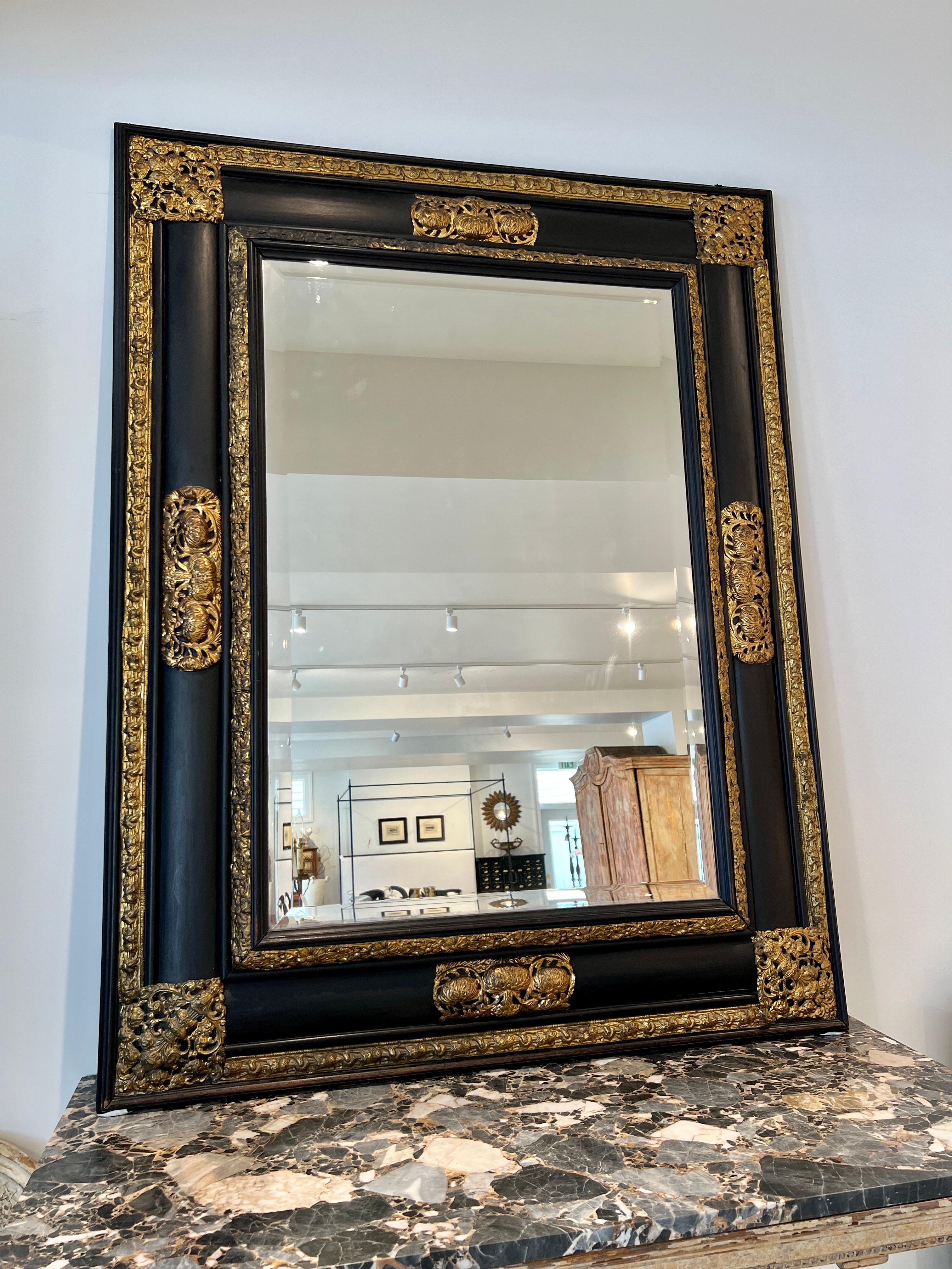 Magnificent, large and wildly elegant mirror in black with extravagant applications of gilded repousse.  This beveled mirror is a standout piece. 