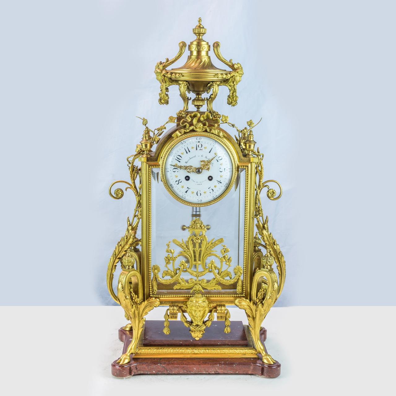 An exquisite 19th century Napoleon III ormolu and rouge griotte marble clock set attributed to Ferdinand Barbedienne. 
Three-piece set comprising a clock and a pair of seven-light candelabra; the clock surmounted by an urn and draped with scrolling