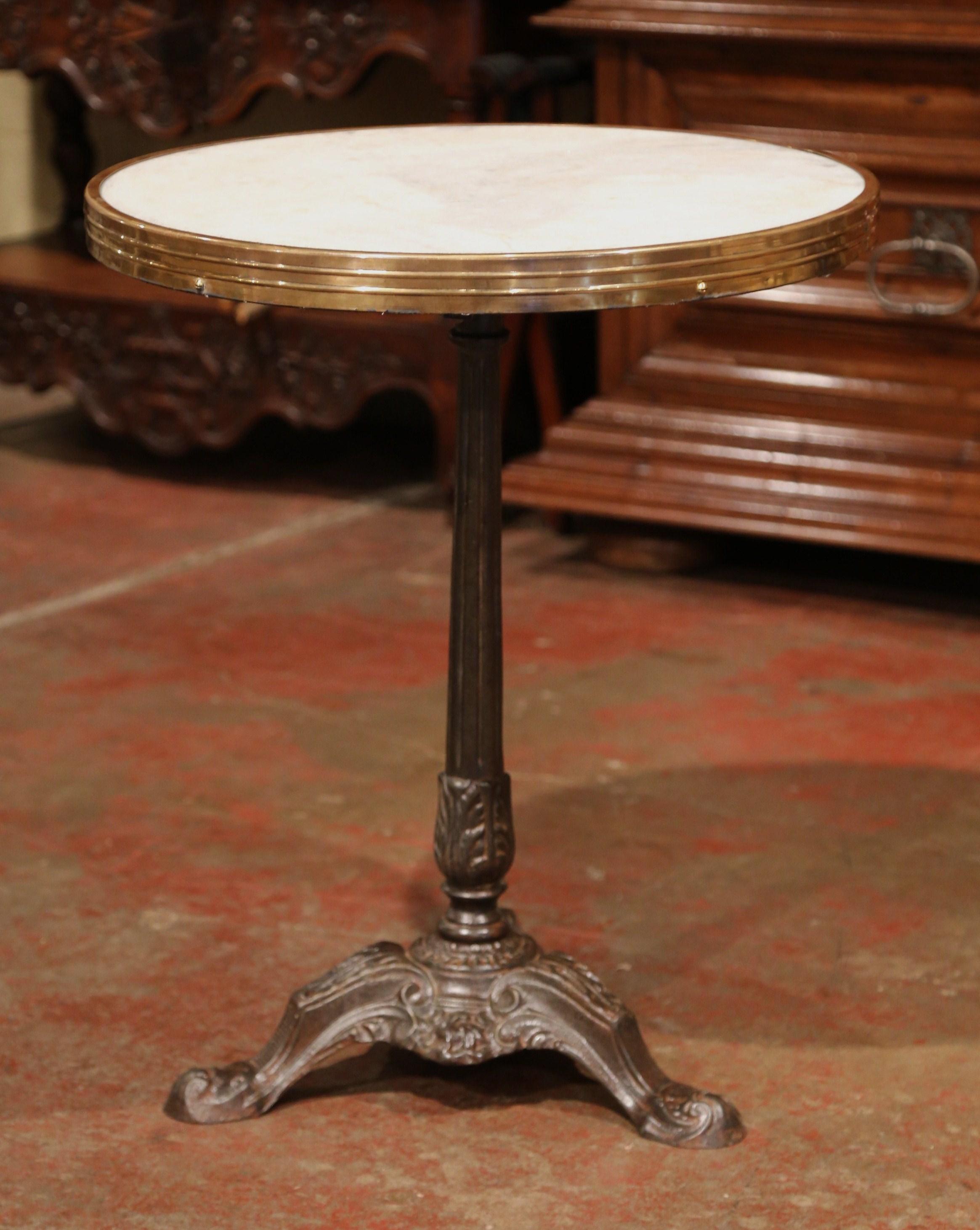 This exquisite, antique gueridon was crafted in Paris, France, circa 1870. The Classic bistrot table features its original, round grey and white marble top embellished by a circular brass trim. The intricate base sits on three feet decorated with