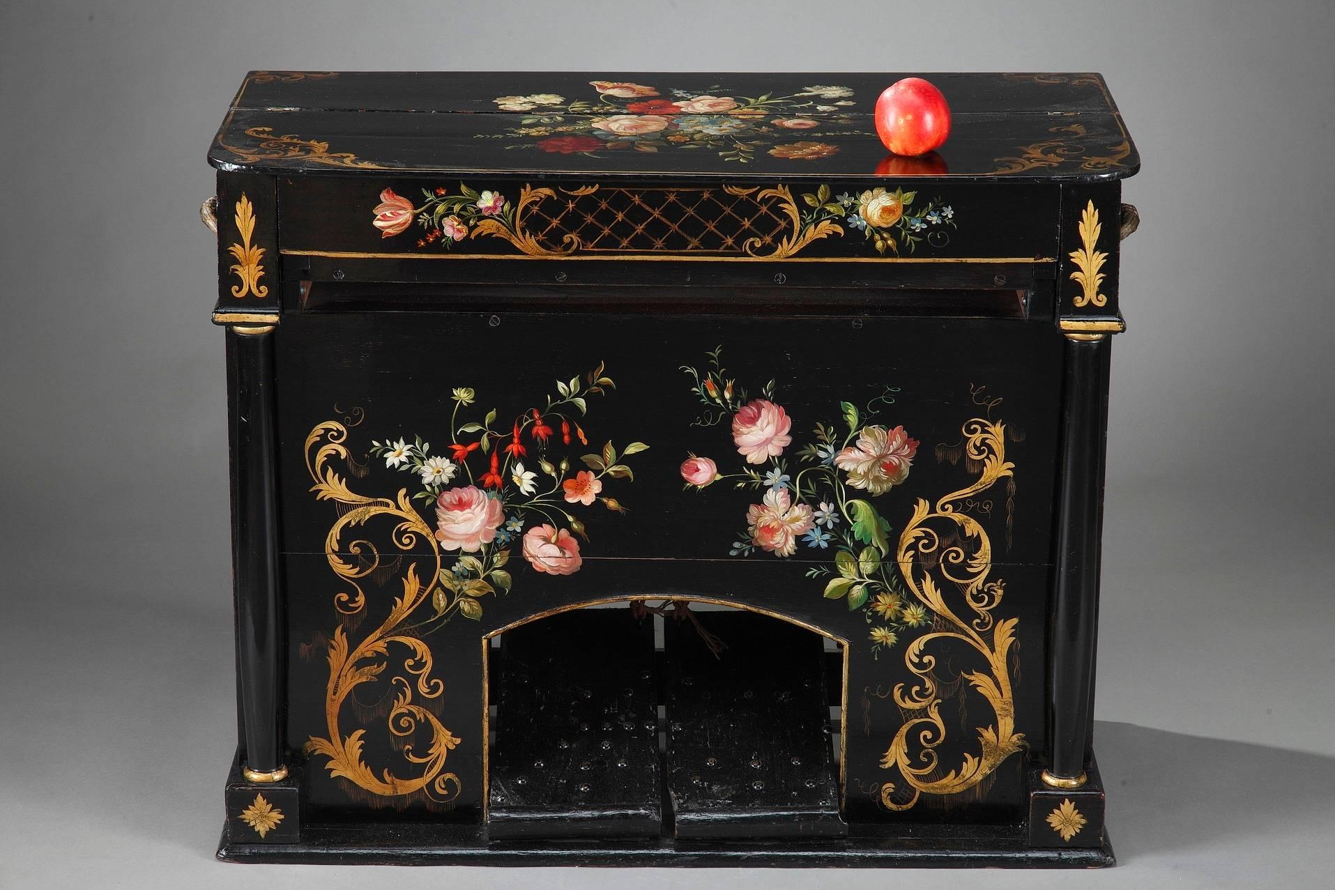 Antique harmonium with pedals and bellow, resting upon a rectangular plinth. Constructed of wood, this organ is richly decorated on all sides with multicolored and golden foliage and flowers on black background. It has two lateral ormolu handles.