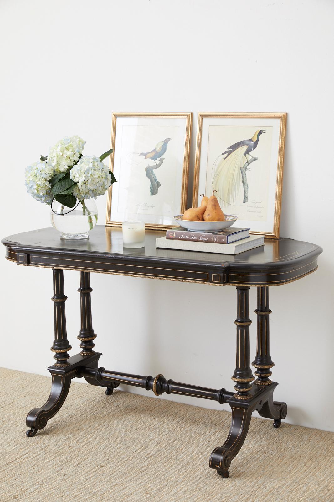 Stunning 19th century Napoleon III center table featuring an ebonized black finish accented by thread inlay and brass mounts. The oval top and base are decorated with delicate inlay and bronze trim. Supported by a four column base each side is