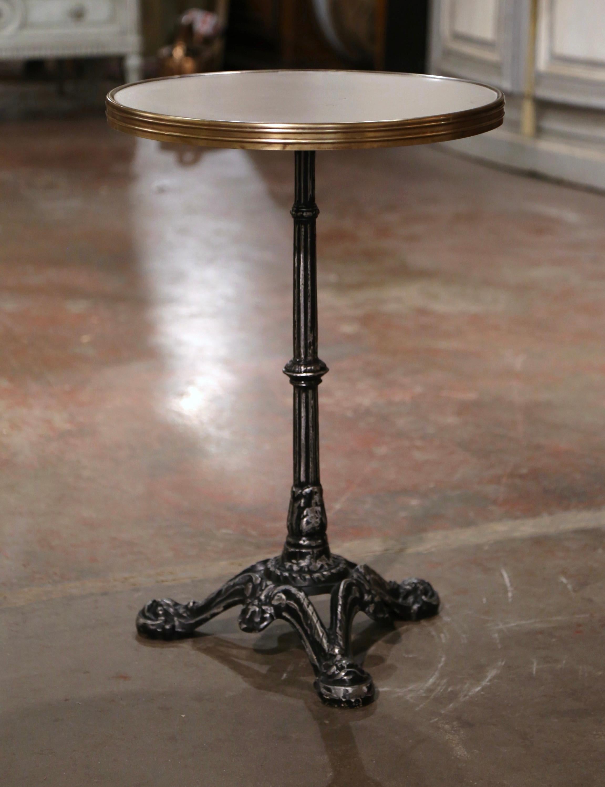 Questo elegante gueridon antico è stato realizzato a Parigi, in Francia, intorno al 1870. L'intricata base in ferro poggia su tre piedi a zampa su un gambo intagliato e impreziosito da motivi di foglie d'acanto. La superficie è rivestita con il