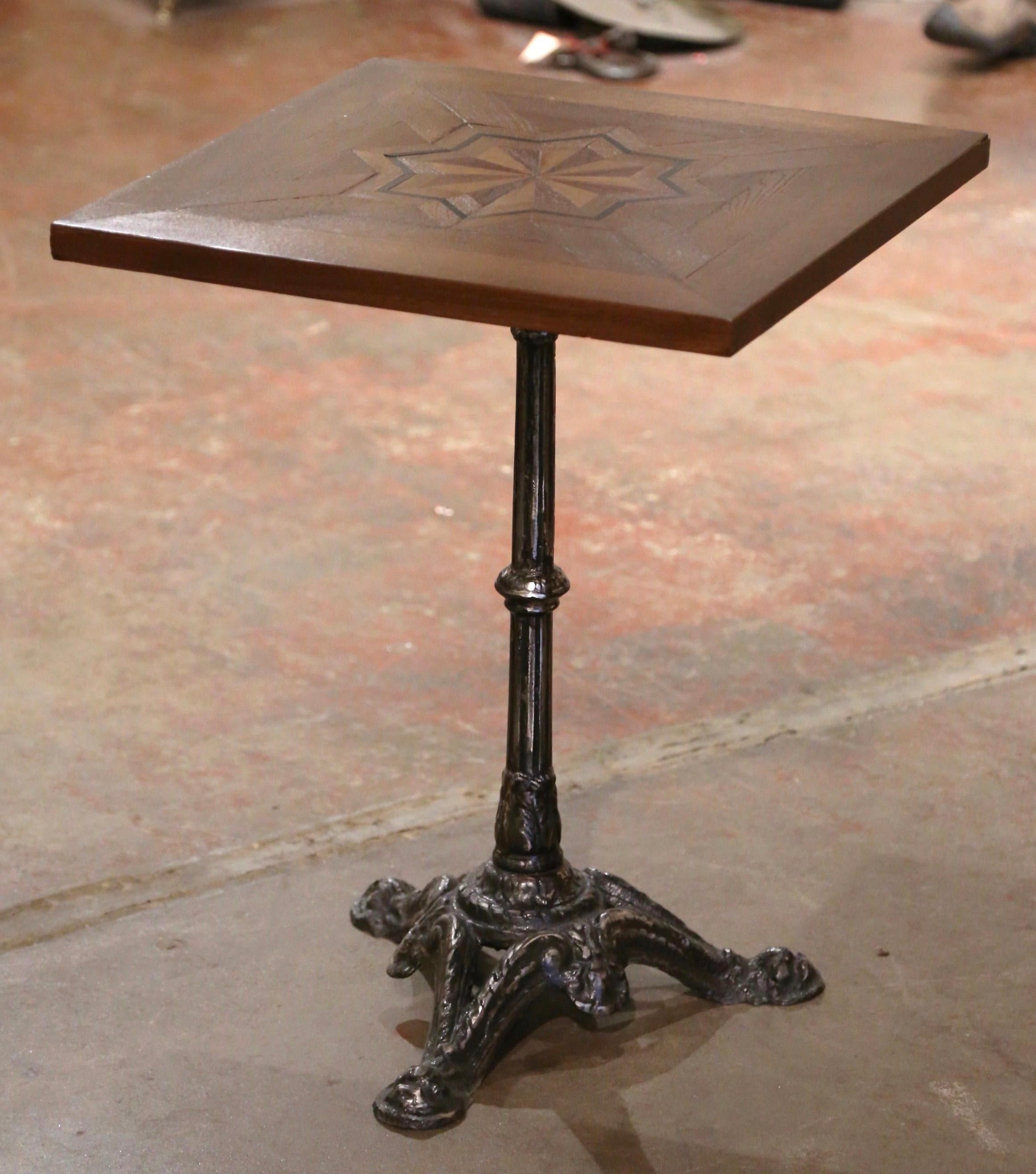 This exquisite, antique gueridon table was crafted in Paris, France, circa 1870. The intricate iron base sits on three paw feet embellished with acanthus leaf motifs over a carved and fluted stem. The classic bistrot base is dressed with a square,