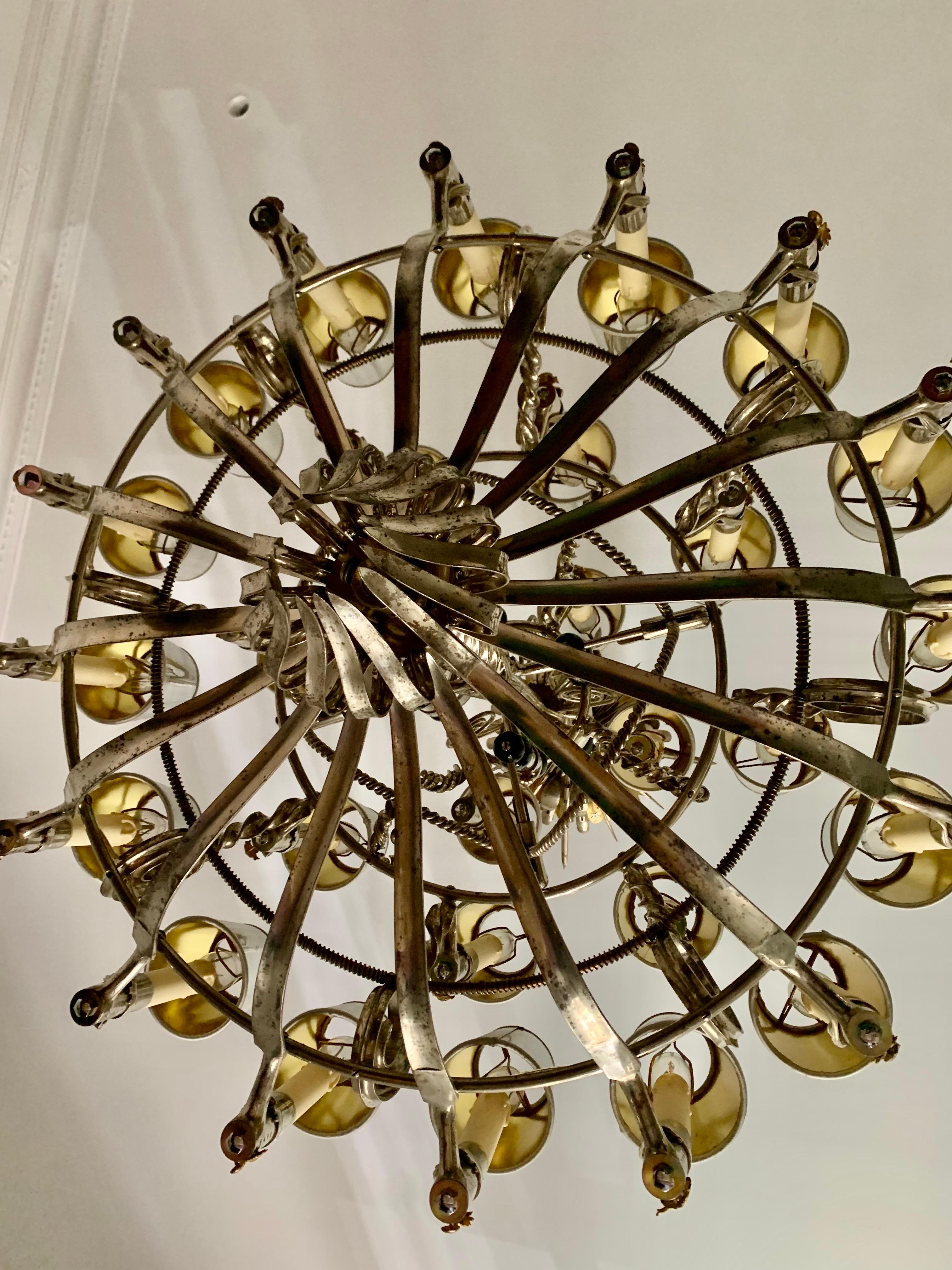 A  exceptional Napoleon III steel twenty eight light chandelier, made from bayonet handles and blades from the Franco/ Prusian war shaped into scrolling branches, each handle with impressed numbers stamps including French M.1822 socket bayonets and