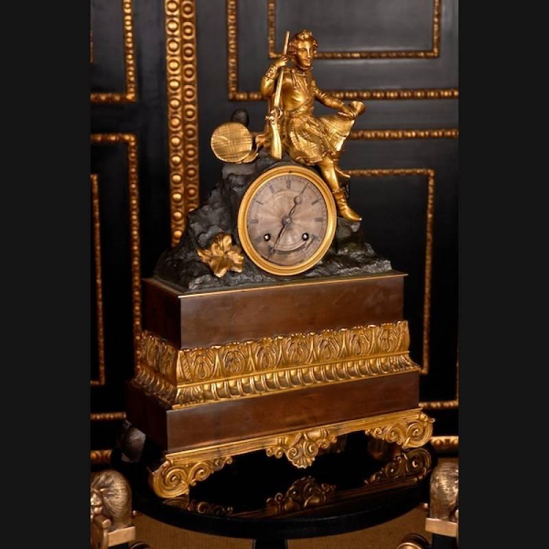 Great empire pendulum / chimney clock, circa 1830-1840 bronze.
Bronze, fire-gilt partially dark brown patinated. Staggered rectangular base on elaborate stand decorated with palms and rosettes. Hunter figure sitting on a round watch case.

(R-12).