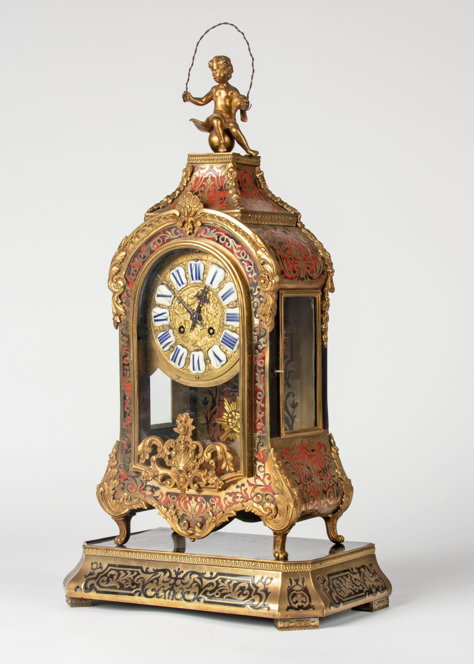 A fine quality French Régence style mantle clock in the style of André-Charles Boulle, with matching base. The cabinet is made of wood, inlaid with engraved brass and red tortoise shell. Embellished with bronze ornaments. The whole is in good