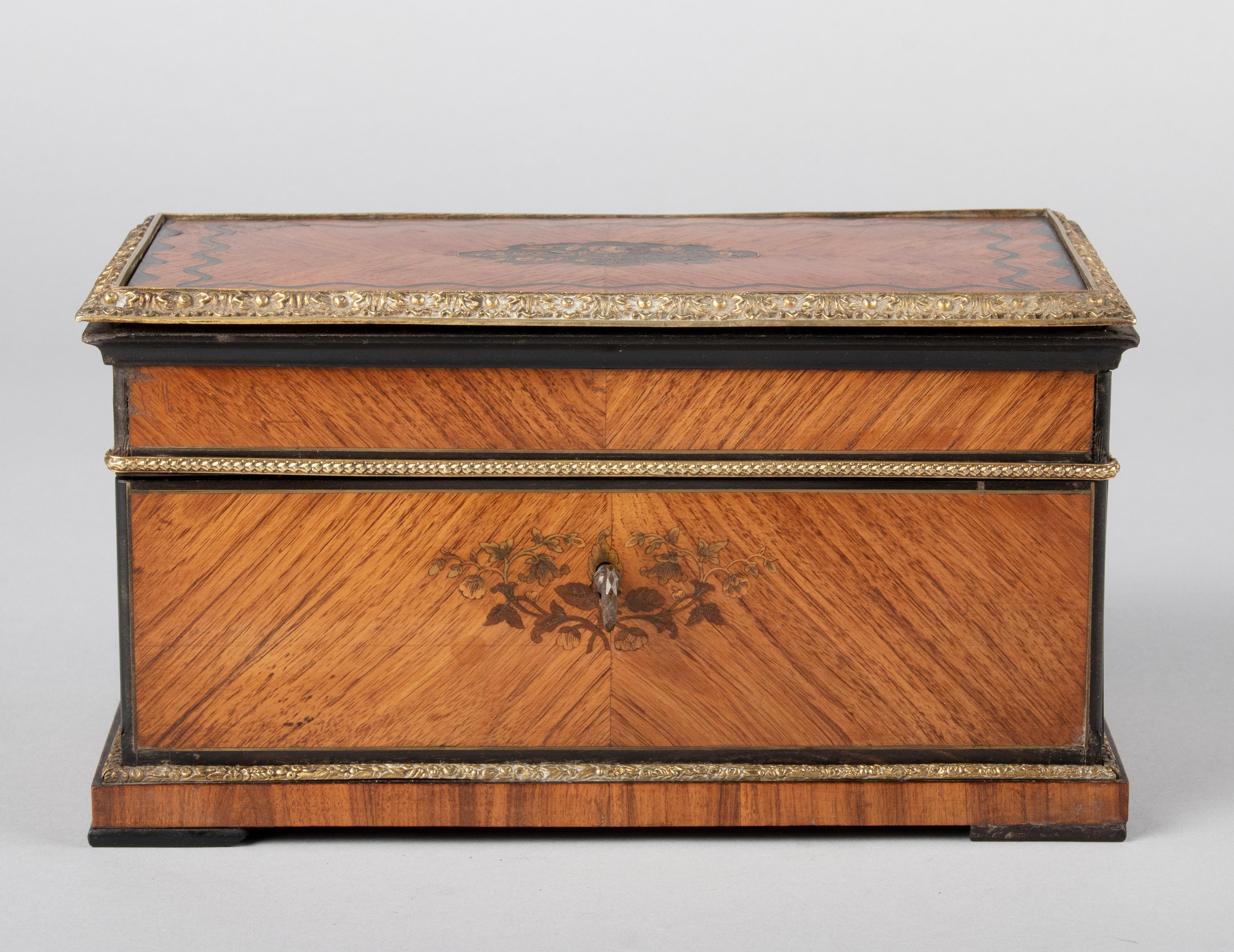 A refined antique French tea caddy from the end of Napoleon III. The box is beautifully inlaid with different types of wood and brass, outside around a bronze rim. Inside two tea boxes made of Birdseye maple wood, the lids have inlay of colored