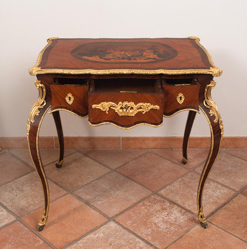 Ancient and elegant small French writing desk from the 19th century, Napoleon III period, made of precious exotic wood with applications in gilded and finely chiselled bronze. The top, also made of exotic wood, features inlaid work of remarkable