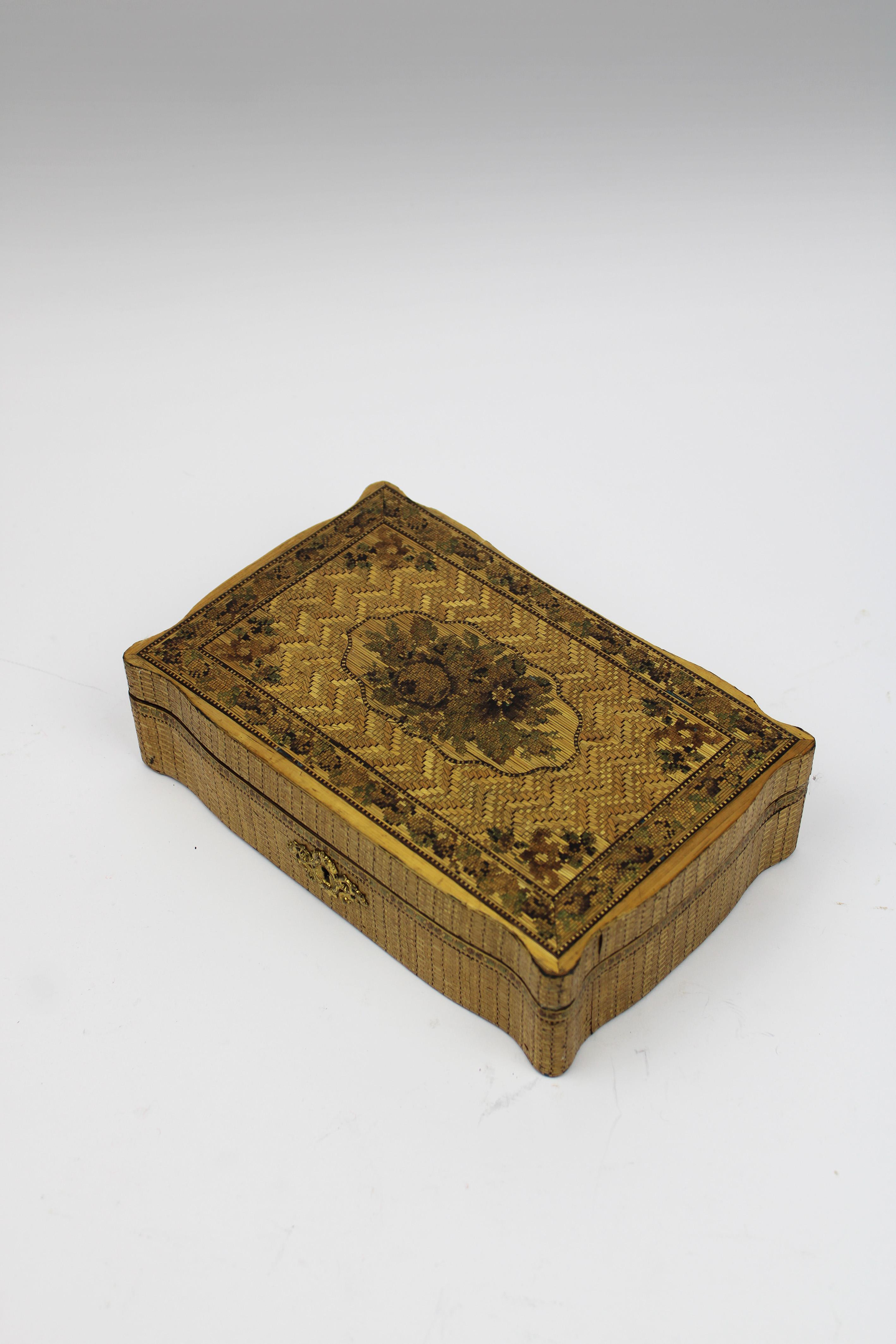 This 19th-century Napoleonic prisoner-of-war marquetry straw veneer box is a remarkable example of the artistry and craftsmanship that emerged from a difficult period in history. Likely created by a skilled cabinetmaker, this box features an unusual