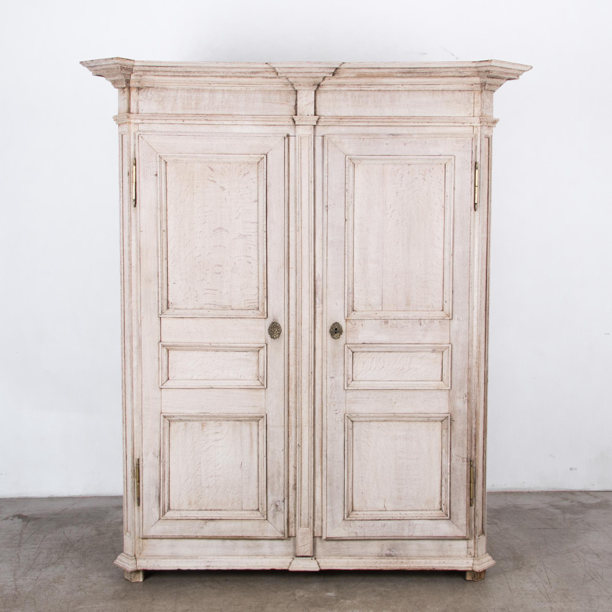 An early 19th century Belgian cabinet from the Narmur region. These distinctive cabinets, with large mouldings and dignified geometric forms, are a regional style influenced by the tradition of French formal furniture. A distinctive light finish