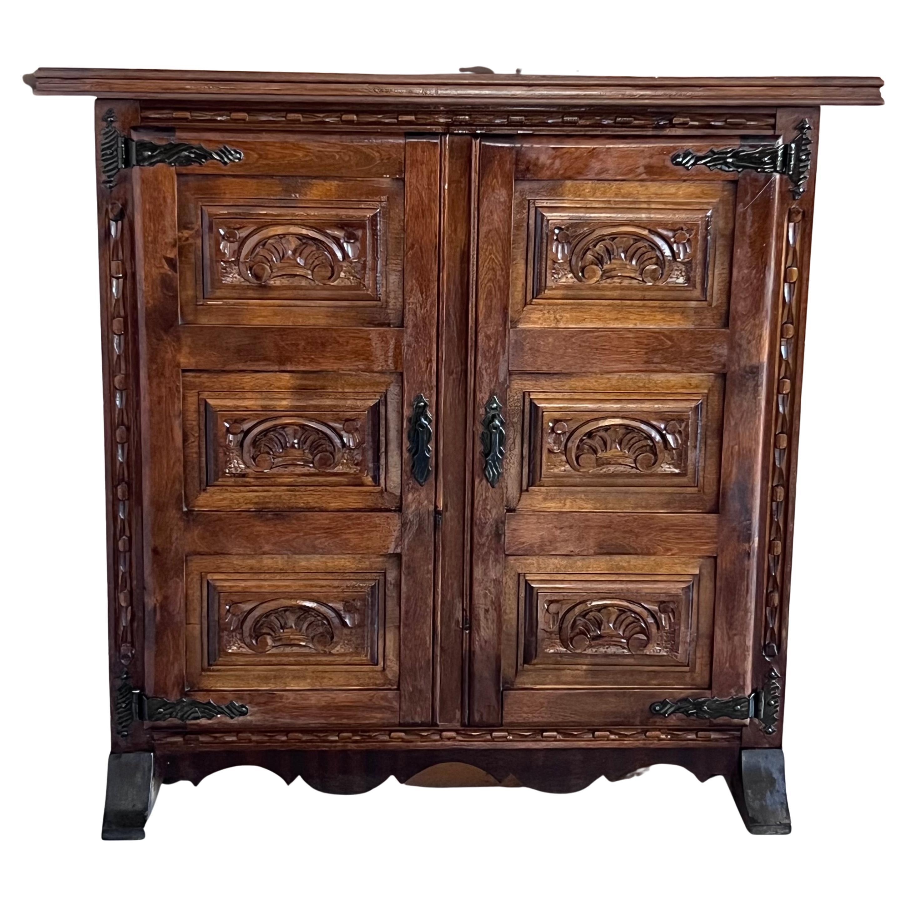 From Northern Spain, constructed of solid walnut, the rectangular top with molded edge atop a conforming case housing two carved doors paneled with solid walnut, raised on a plinth base.
Very heavy and original cabinet.

WE WILL RESTORE THE PIECE