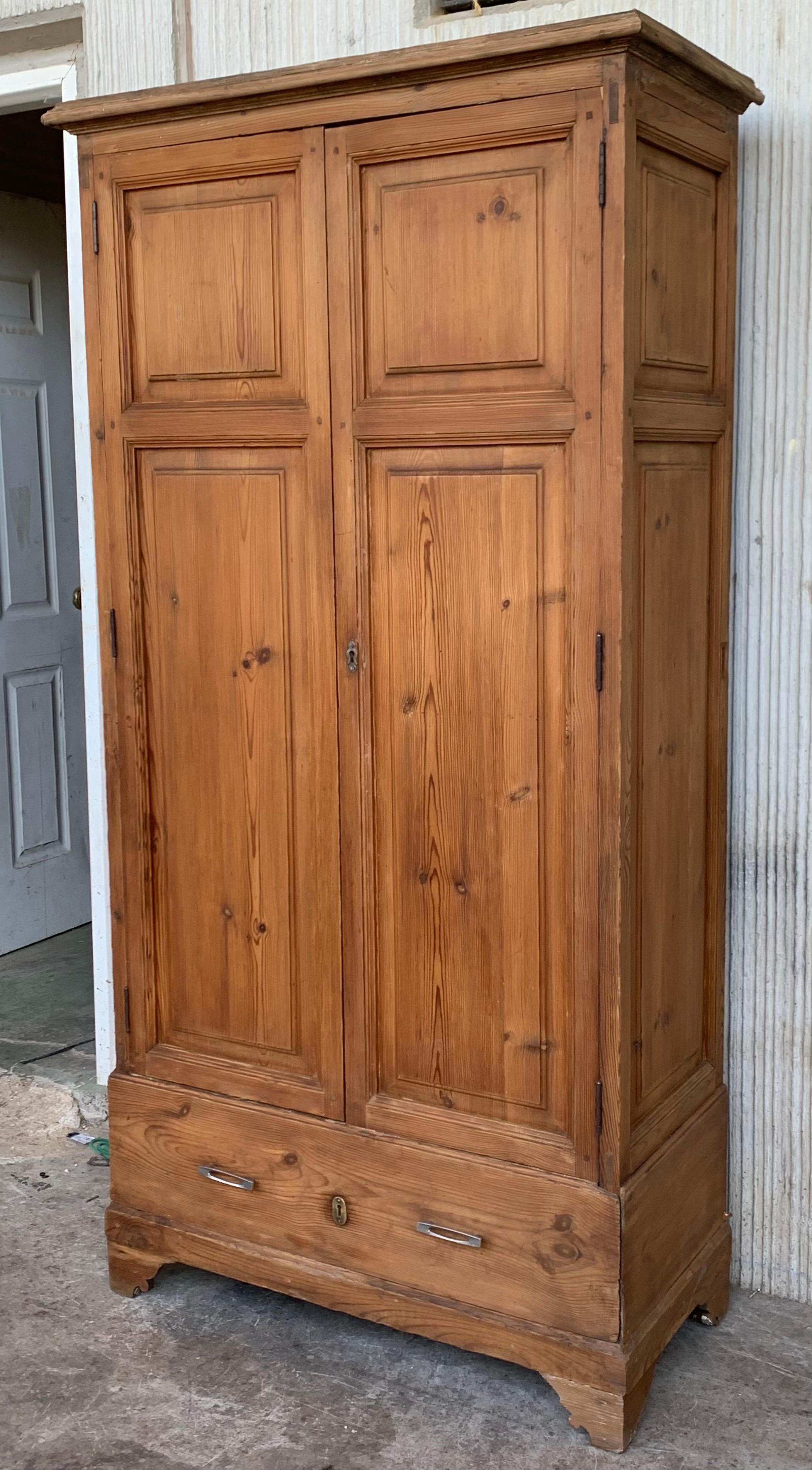 Pine narrow 20th century Spanish cabinet constructed from pine. Features a coffered case fronted by two doors in the high part and one drawer in the low part. This massive cabinet made in Spain features beautiful pine grain and showcases the amazing