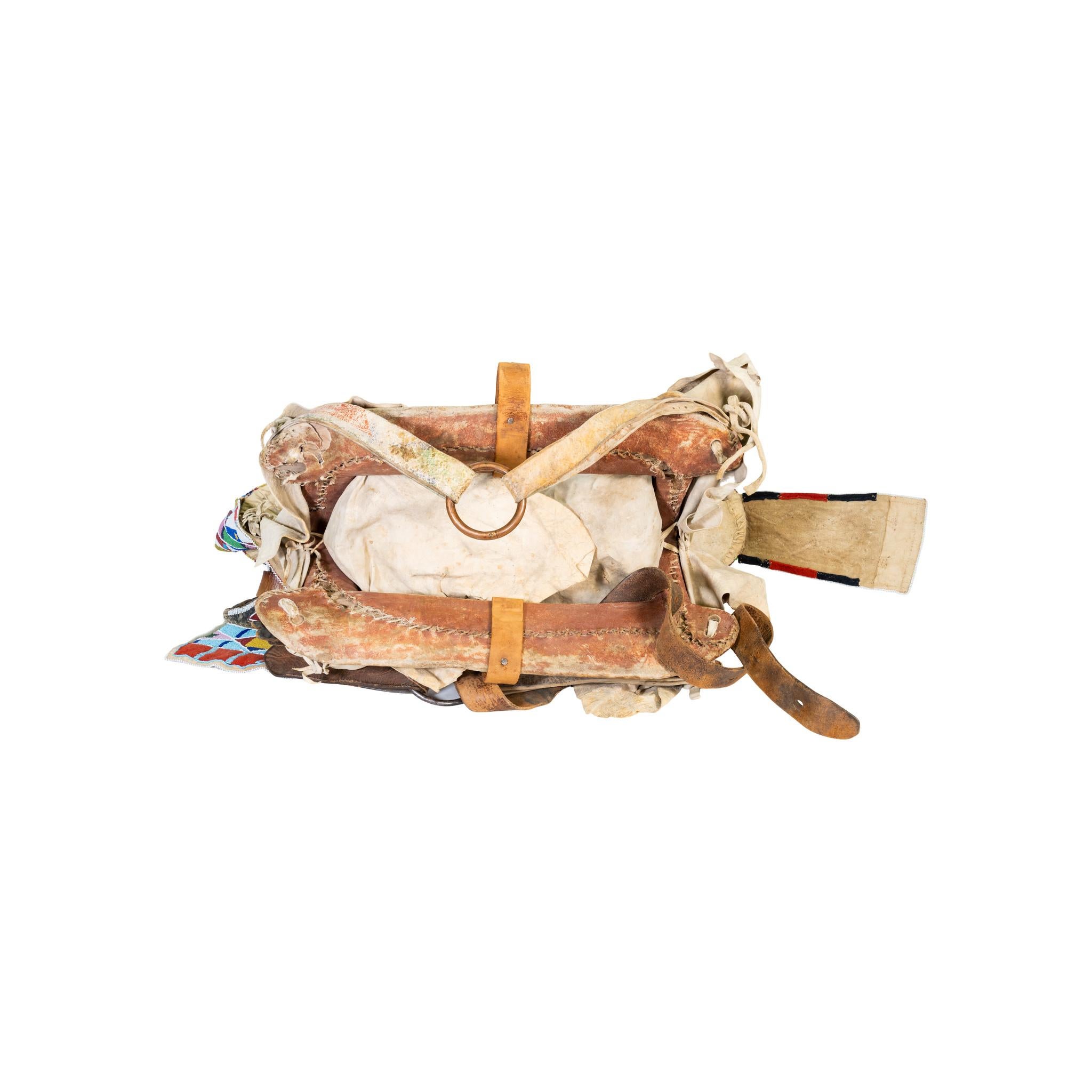 Sella di corvo autentica con pelle di cervo conciata al cervello. Corna e gocce di perline originali. Staffe originali in legno e cuoio con gocce collegate con cinghie di cuoio da sella. Tre delle cinghie di collegamento della sella sono di bufalo
