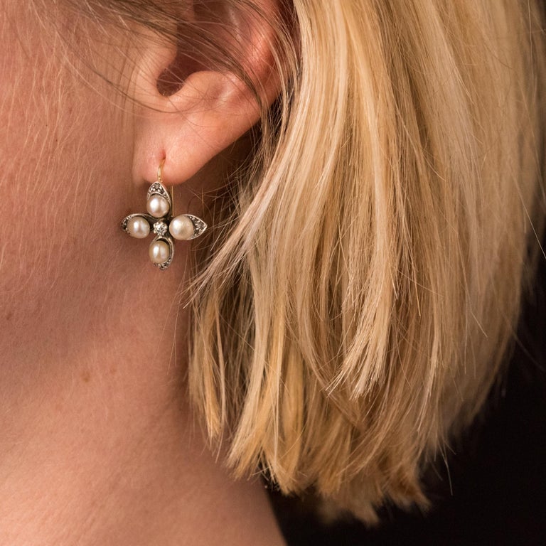 Earrings in 14 karats yellow gold.
Lovely antique lever- back earrings, each is set with 4 half natural pearls on a 4 leaves clover decoration set with rose- cut diamonds. In the center, a antique brilliant- cut diamond is set with claws. The clasp