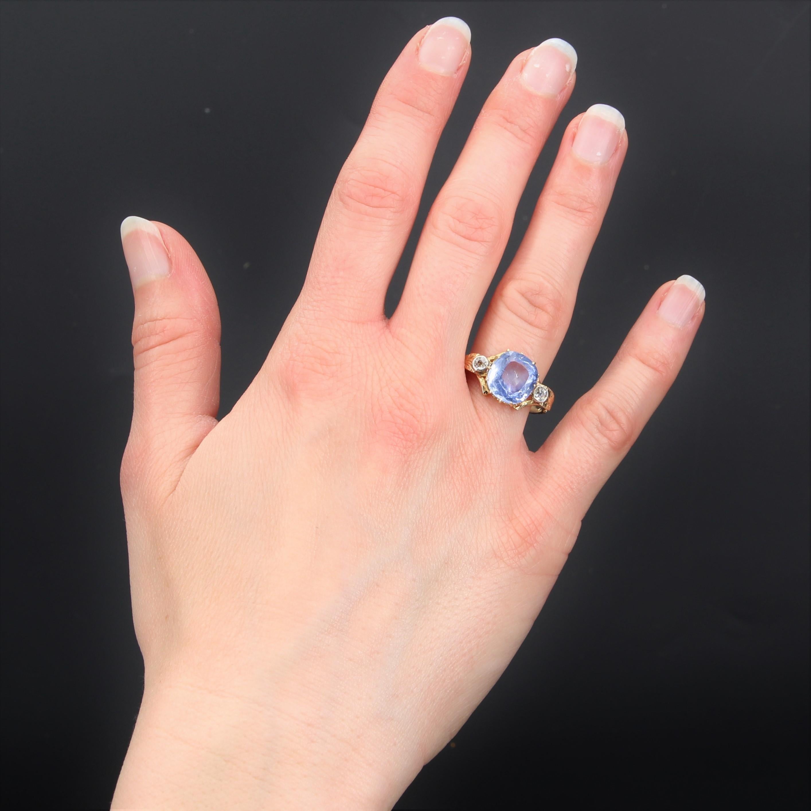 Ring in 18 karat yellow gold.
Superb antique ring set with claws on its top of a cushion- cut blue sapphire, shouldered by two antique brilliant- cut diamonds which are supported by two chiseled gold leaves. The rest of the ring is worked with