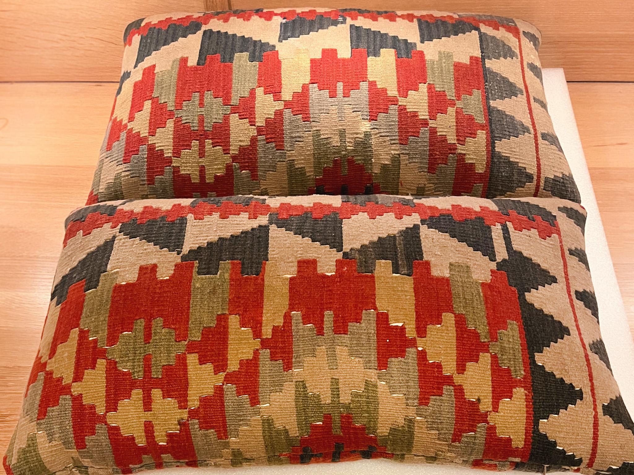 Questi due cuscini sono stati realizzati su misura con coperte di lana Navajo del XIX secolo. Il tessuto è intrecciato a mano in un disegno di triangoli geometrici intrecciati, in una vibrante tavolozza di blu, rossi, giallo pallido e beige. I