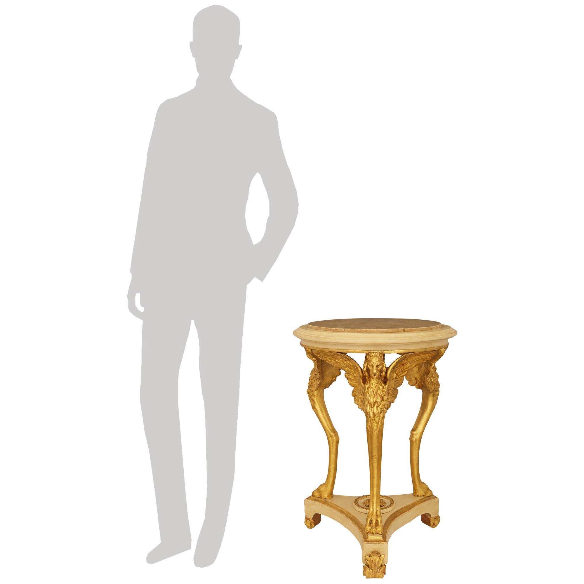 Très belle et très décorative table d'appoint en bois patiné, bois doré et marbre de style néo-classique italien du XIXe siècle. Cette magnifique table circulaire patinée blanc cassé repose sur une base triangulaire aux côtés concaves, accentuée par