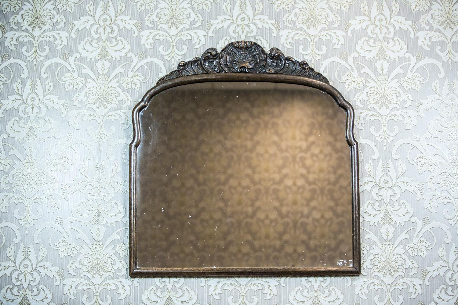 We present you this mirror, circa the late 19th century, closed in a wooden frame in the Neo-Rococo style.
The shape of the mirror is similar to a square. The frame is topped with a semi-plastic decoration with the motif of a shell.

Presented