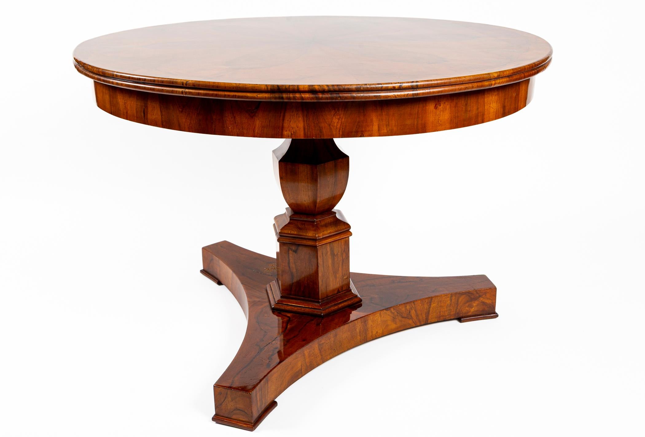 An exquisite Neoclassical Biedermeier circular center table with a stunning piecrust walnut veneer plateau of a large petal starburst above a modified classical pedestal column finishing on a tripartite base.

Origin: Southern Germany
Dating: