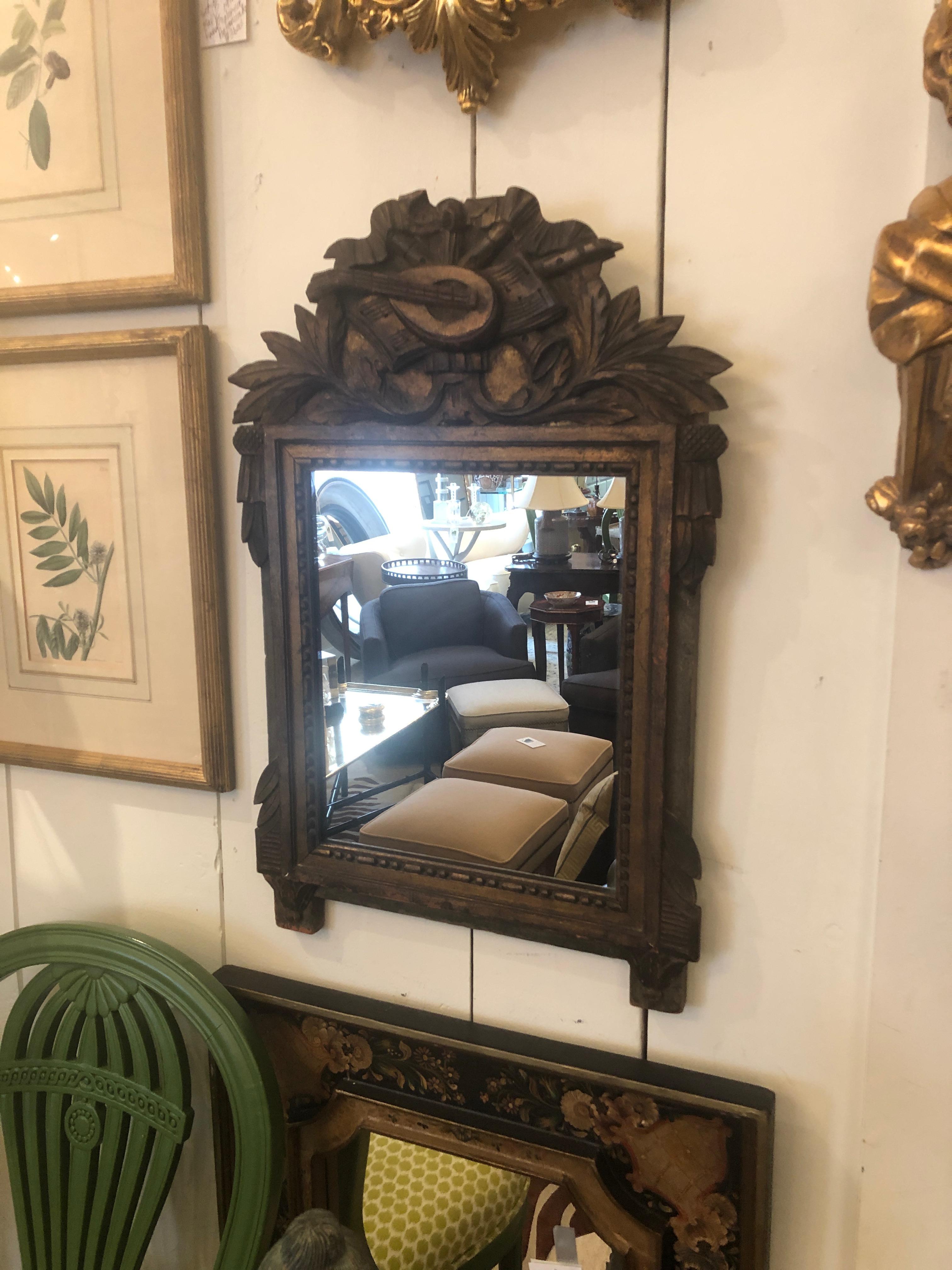 Authentic 19th century French carved giltwood small wall mirror having neoclassical design with mandolin at the top.