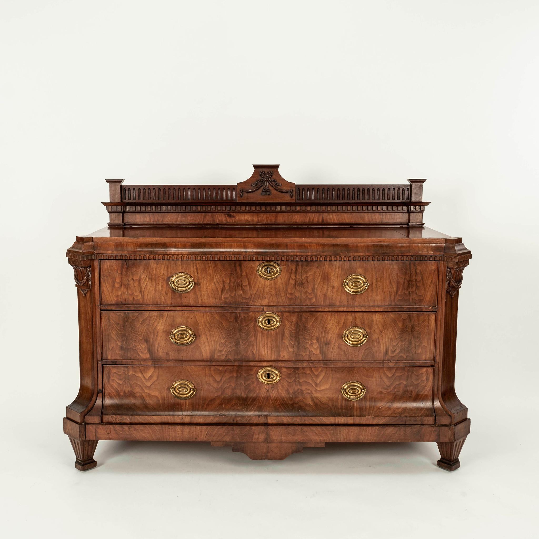 An early 19th Century Northern European neoclassical walnut commode with three drawers and brass pulls.