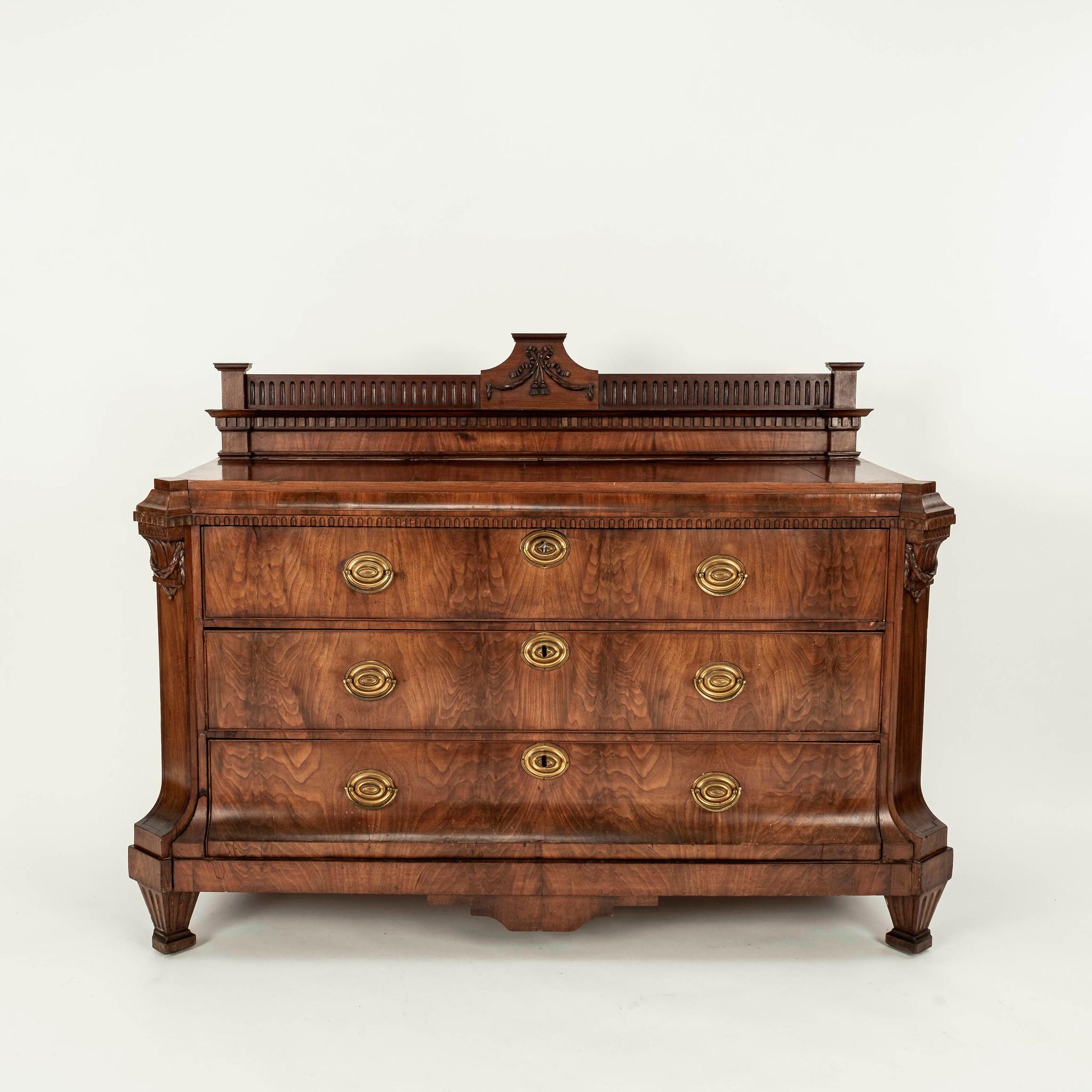 An early 19th Century Northern European neoclassical walnut commode with three drawers and brass pulls.