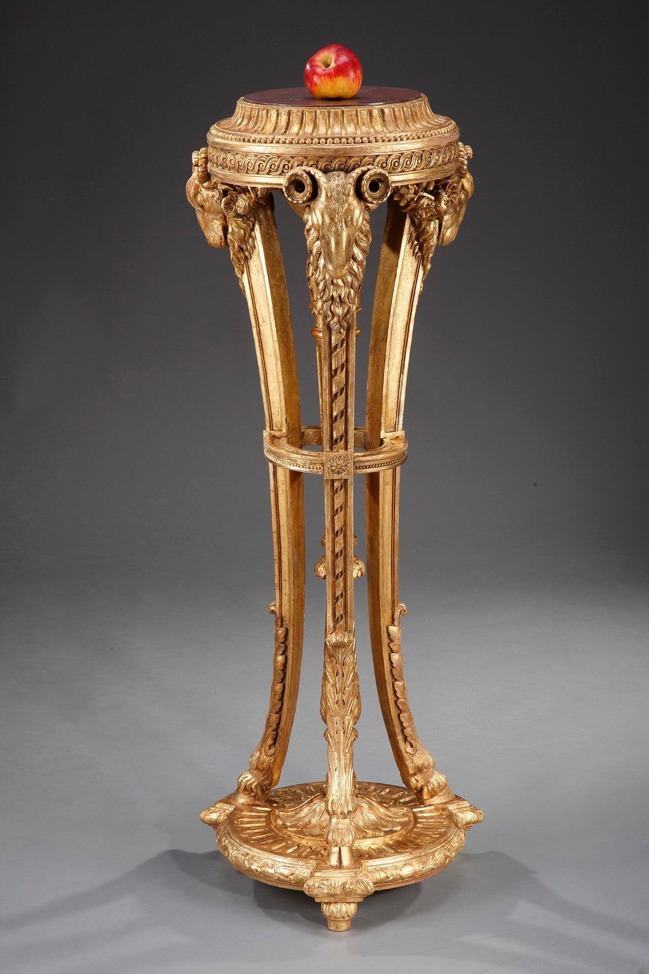 19th century neoclassical pedestal resting on three arched hoof's paw feet, above a round base. Crafted of giltwood, this intricately detailed fixure boasts rams' heads, garlands of flowers and acanthus leaves. The upper part with circular red