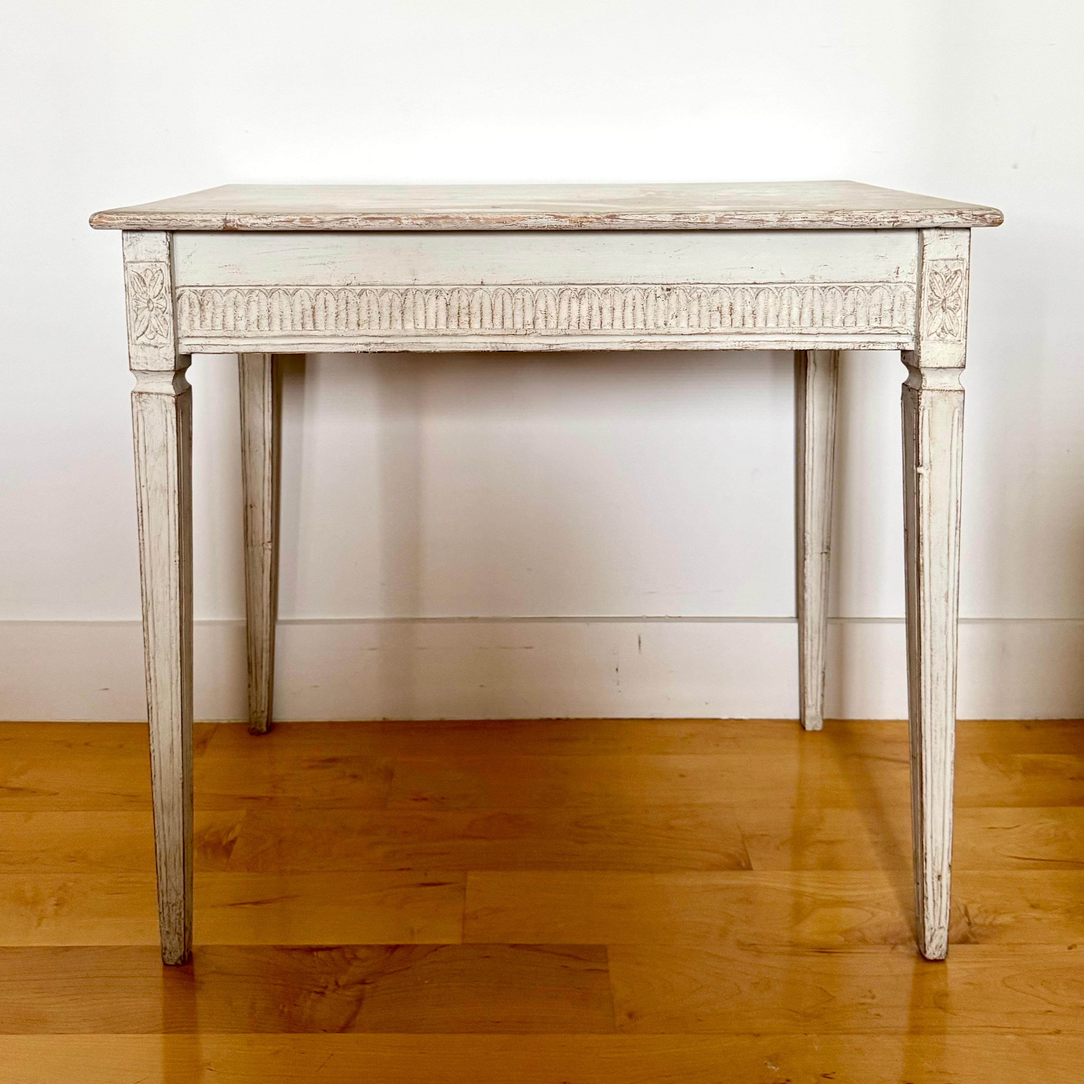 Swedish Gustavian style painted wood side table/center table/small writing table  from the late 19th century, with reeded aprons and tapered legs, rectangular top accented with reeded all sides reeded apron. It is raised on four tapered legs with