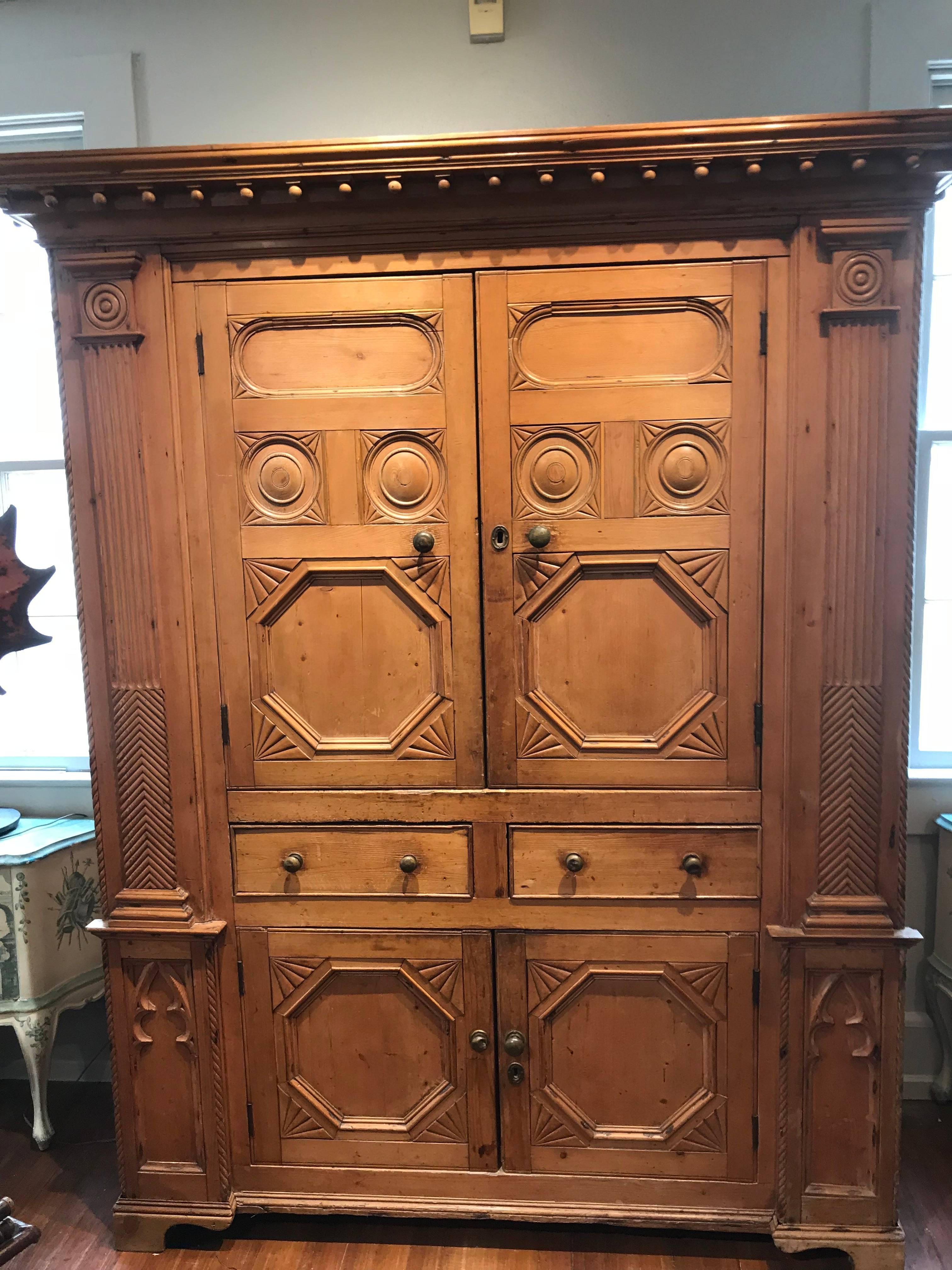 This extremely rare 19th century neoclassical revival Irish pine cabinet is a beautiful way to store your things. Two cupboard doors on top concealing two shelves, two drawers in center and two smaller cupboard doors hiding one shelf. Golden colored