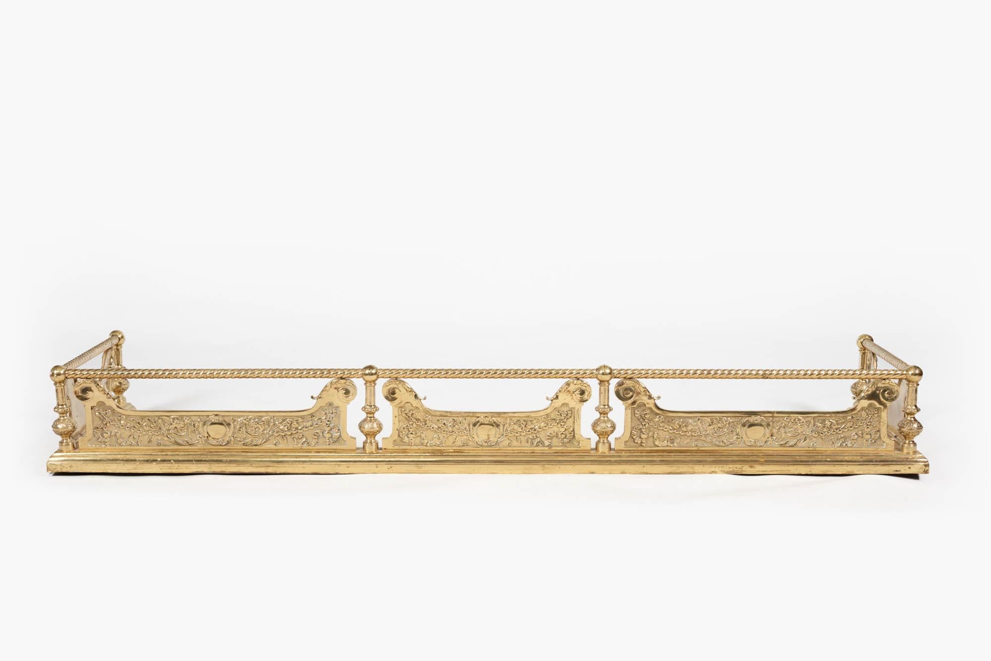 19th Century heavy brass fender in the Neoclassical style with barley twist toprail and cast brass foliate panels with swag and acanthus leaf decoration, divided by simple baulistered columns and post corners.