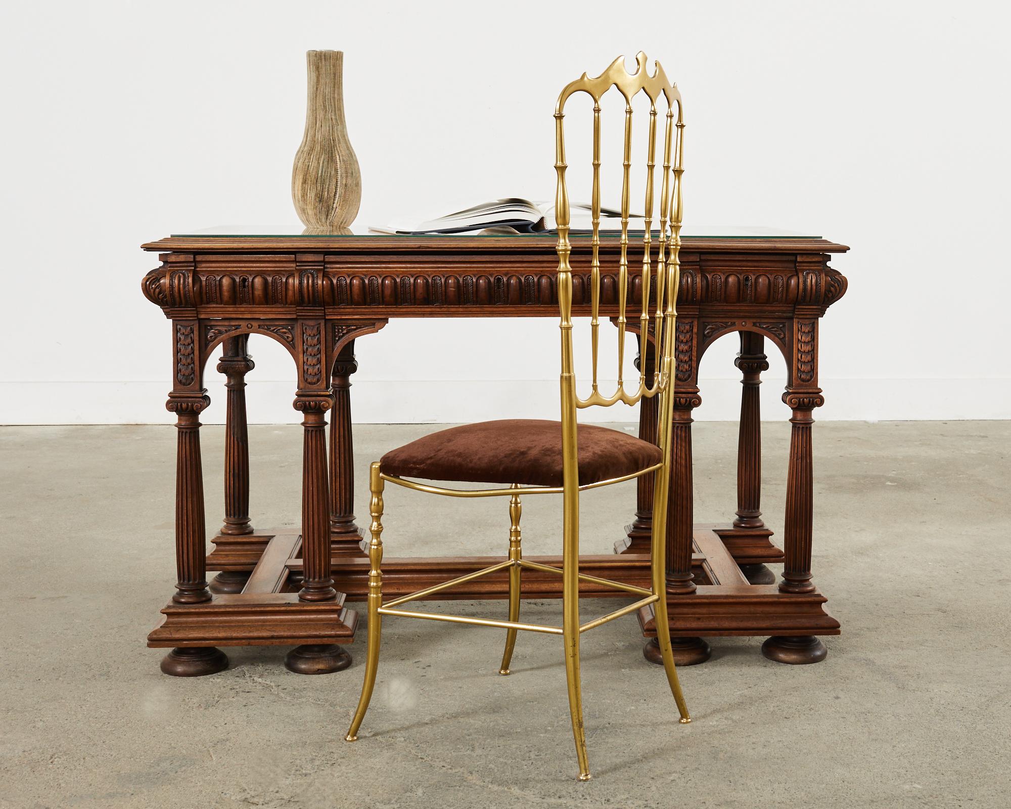 Dramatic 19th century English library table, writing table, or desk hand-crafted from oak. The table features a trestle style base with Greco-Roman corinthian columns in the neoclassical taste. The columns are supported by an H shaped stretcher
