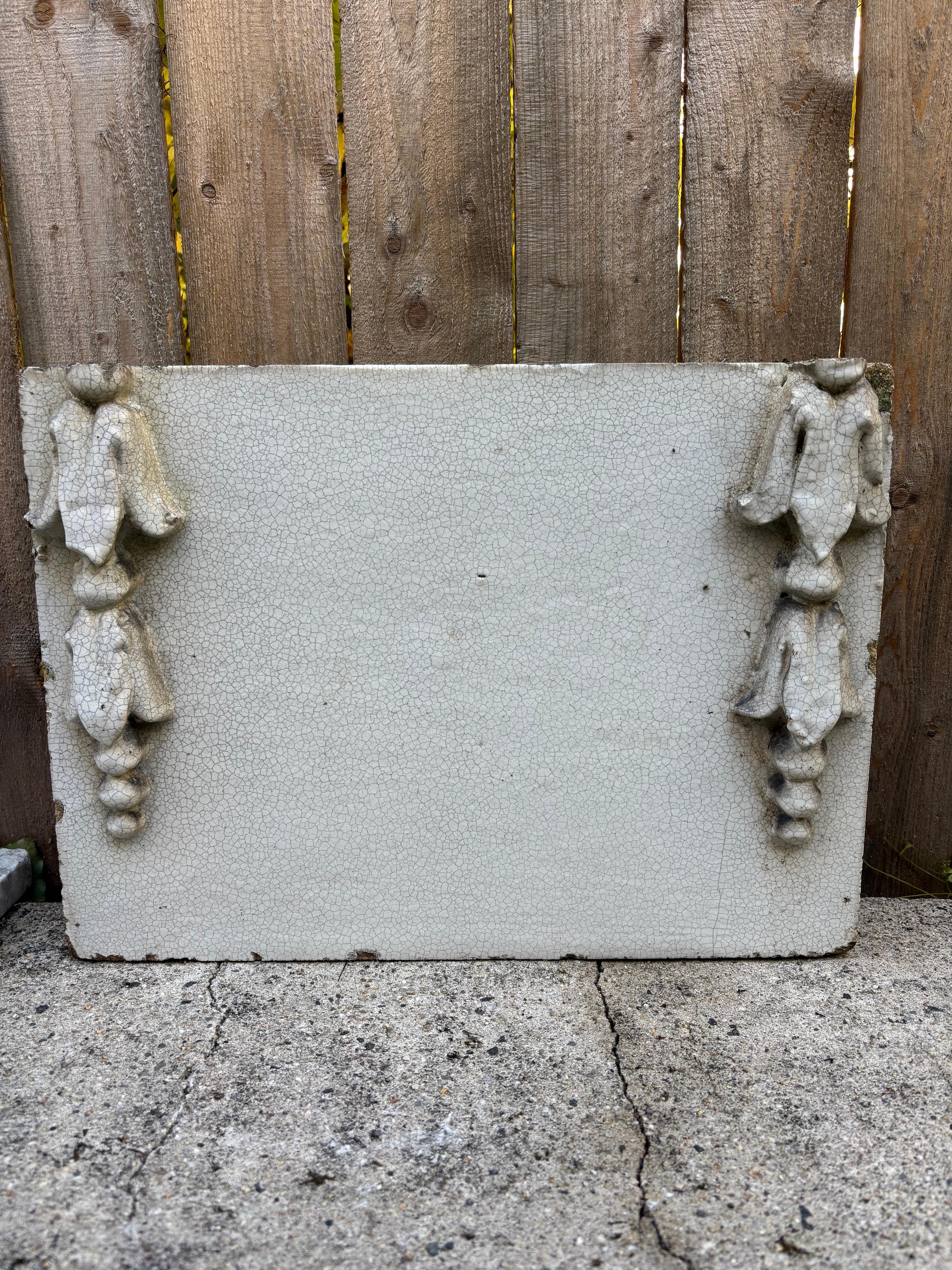 19th century terracotta architectural element with white glaze. The panel is decorated with bell flowers on either side. This piece has a wonderful craquelure surface, with crazing that only comes with age and exposure to the elements. A great