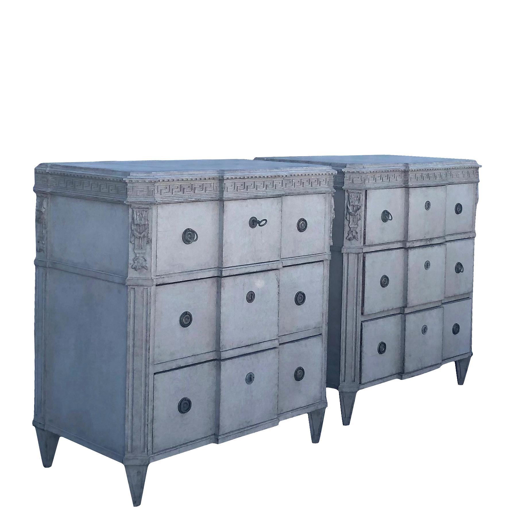 A pair of antique Gustavian neoclassical breakfront chests with three drawers, made of a light grey painted pinewood. The Swedish hand carved chests are in good condition, highly detailed in the Neoclassical Greek style with their original hardware.