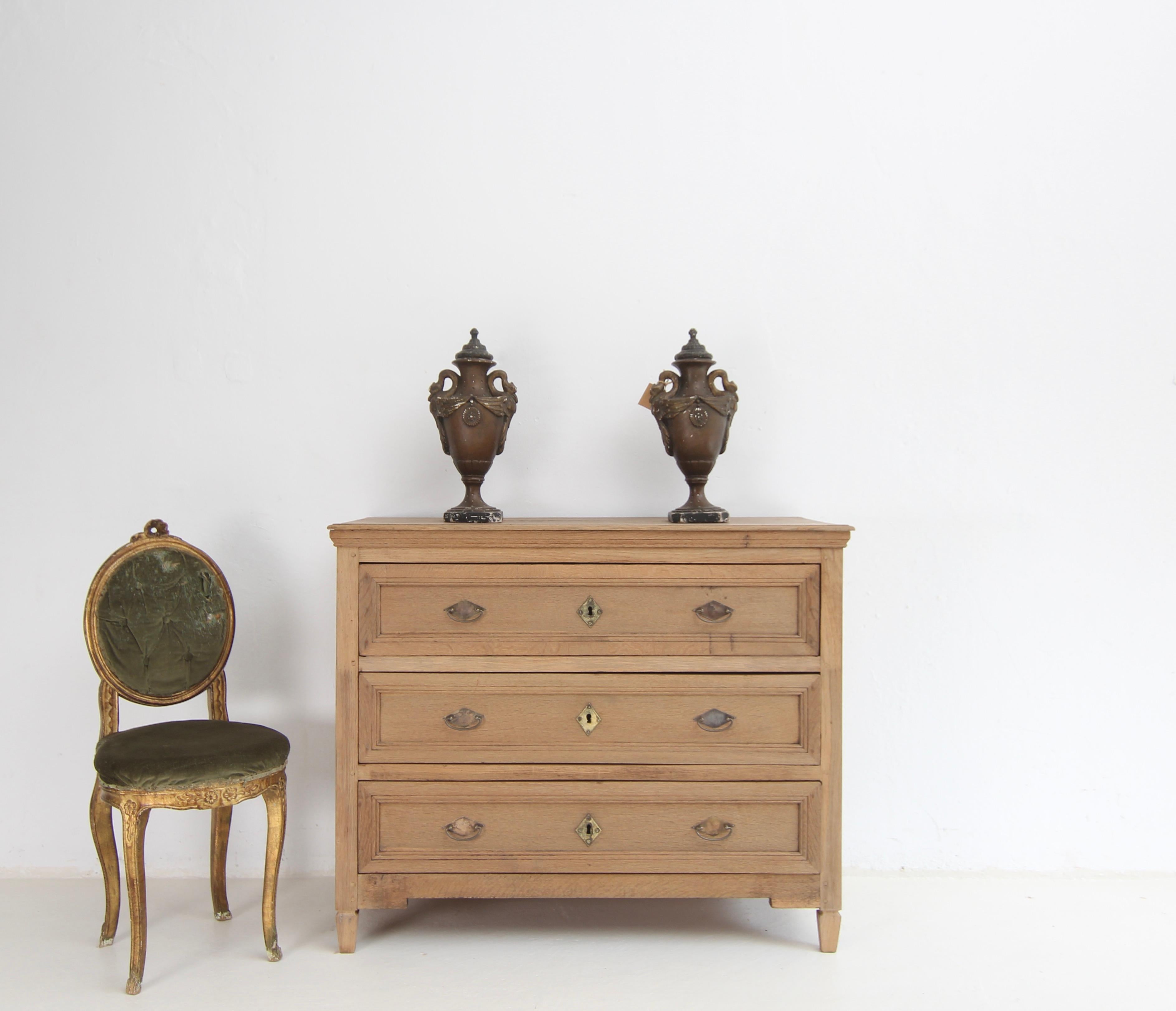A neoclassicist chest of drawers from the 1st half of the 19th century. Made from solid oak.

Very attractive combination of classic design with the natural surface of raw oak wood.

On tapered square feet, straight, laterally coffered oak body in
